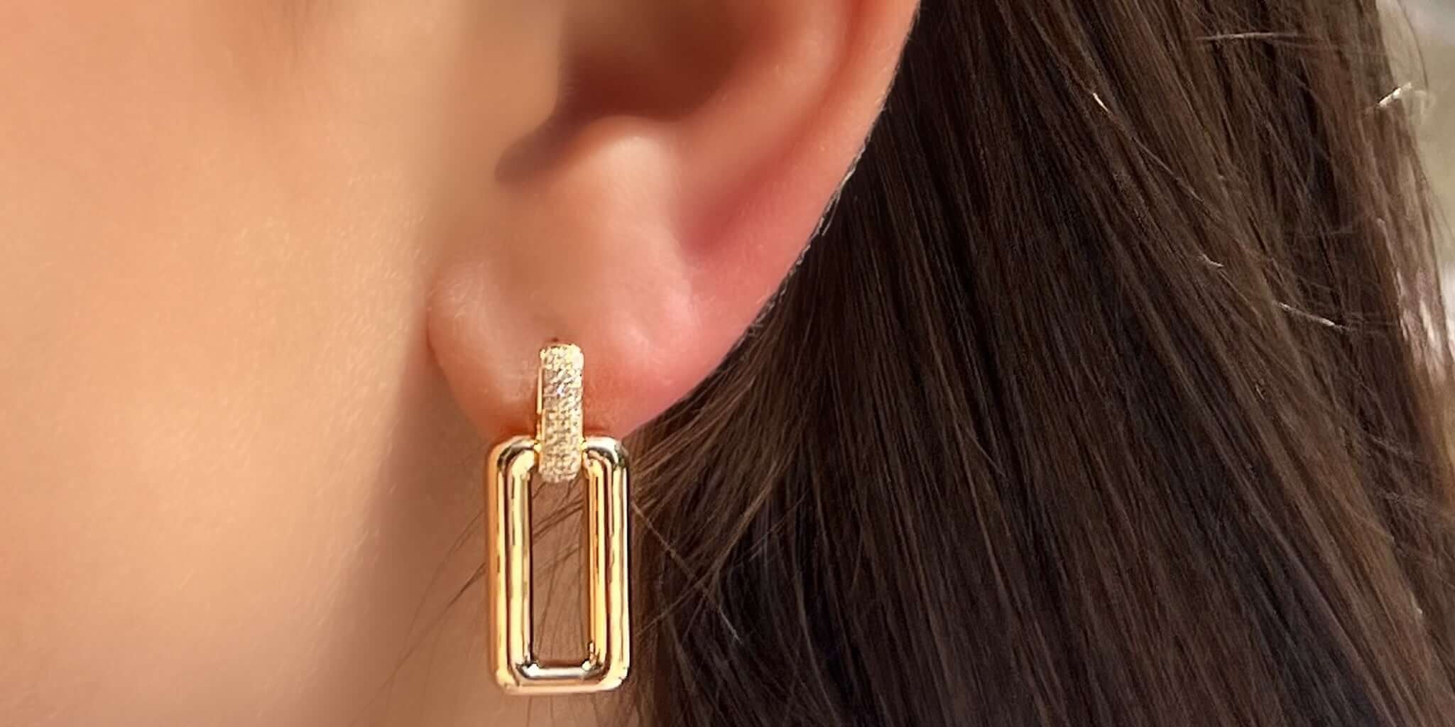 Stylish gold drop earrings featuring a unique geometric design, worn on a model's ear.