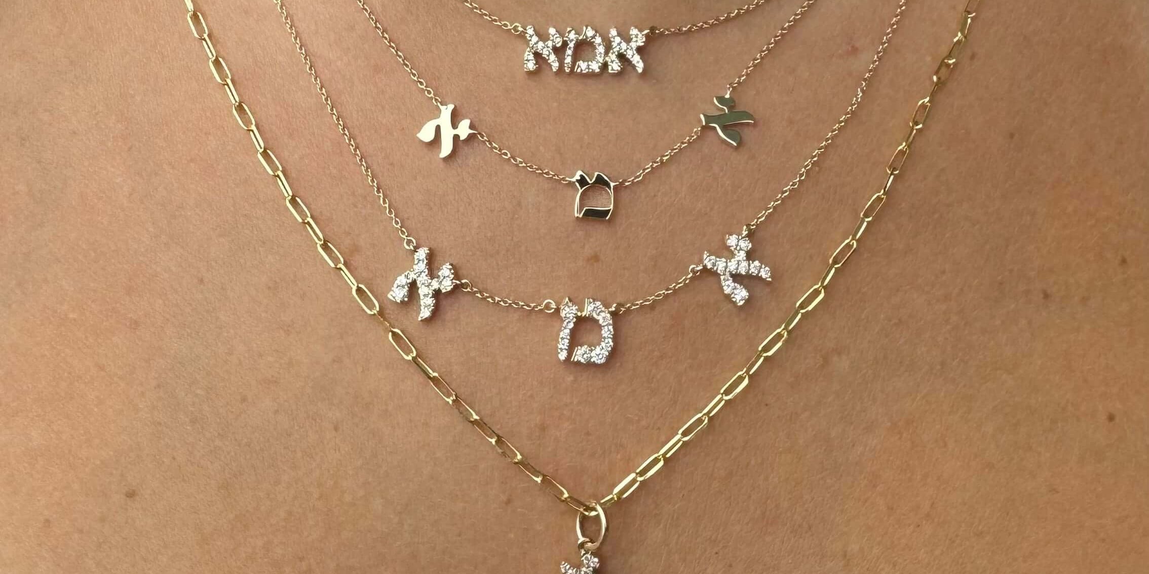 Elegant layered necklaces featuring Hebrew letters in gold and silver, showcasing a unique cultural jewelry collection.