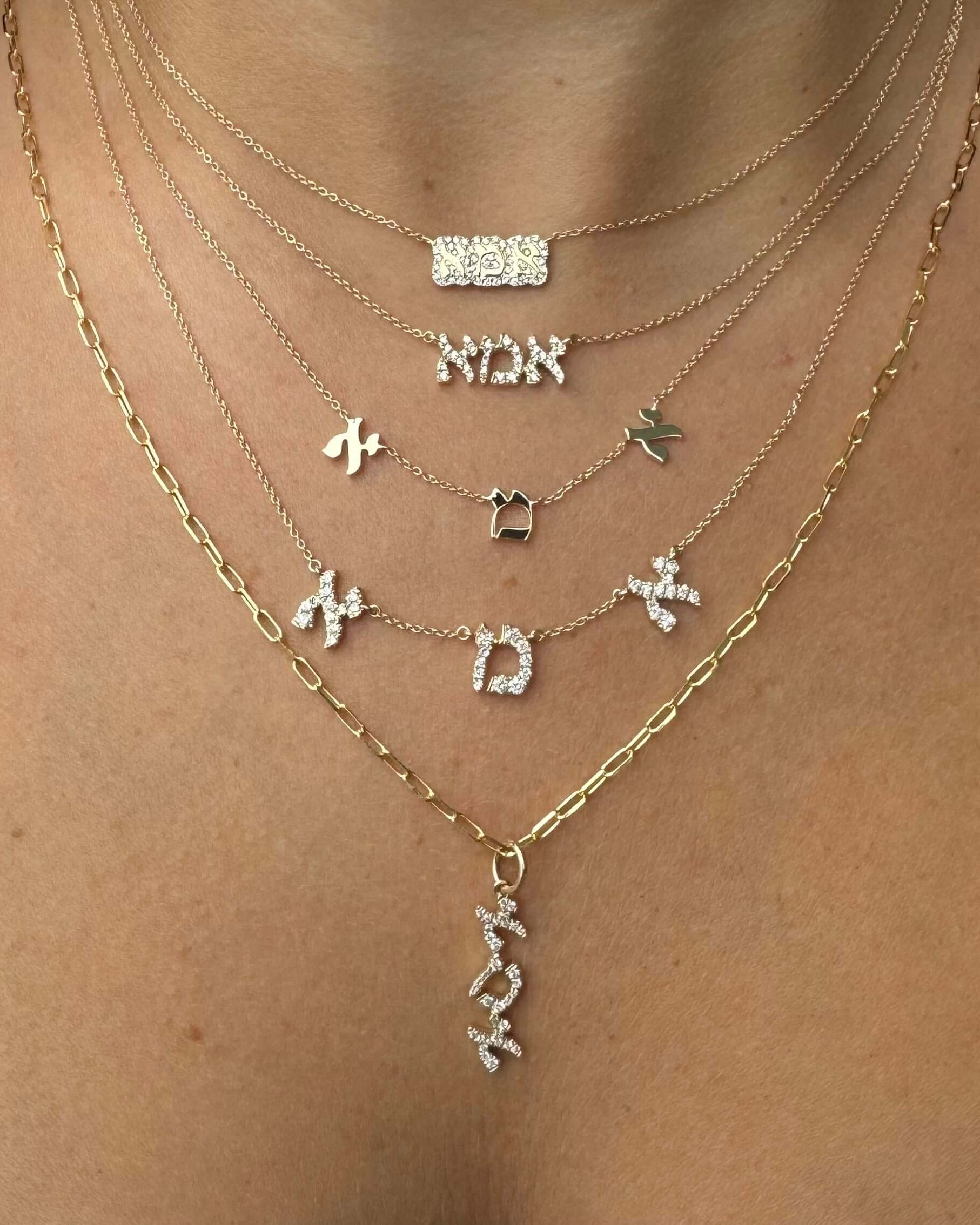 Elegant layered necklaces featuring Hebrew letters in gold and silver, showcasing a unique cultural jewelry collection.