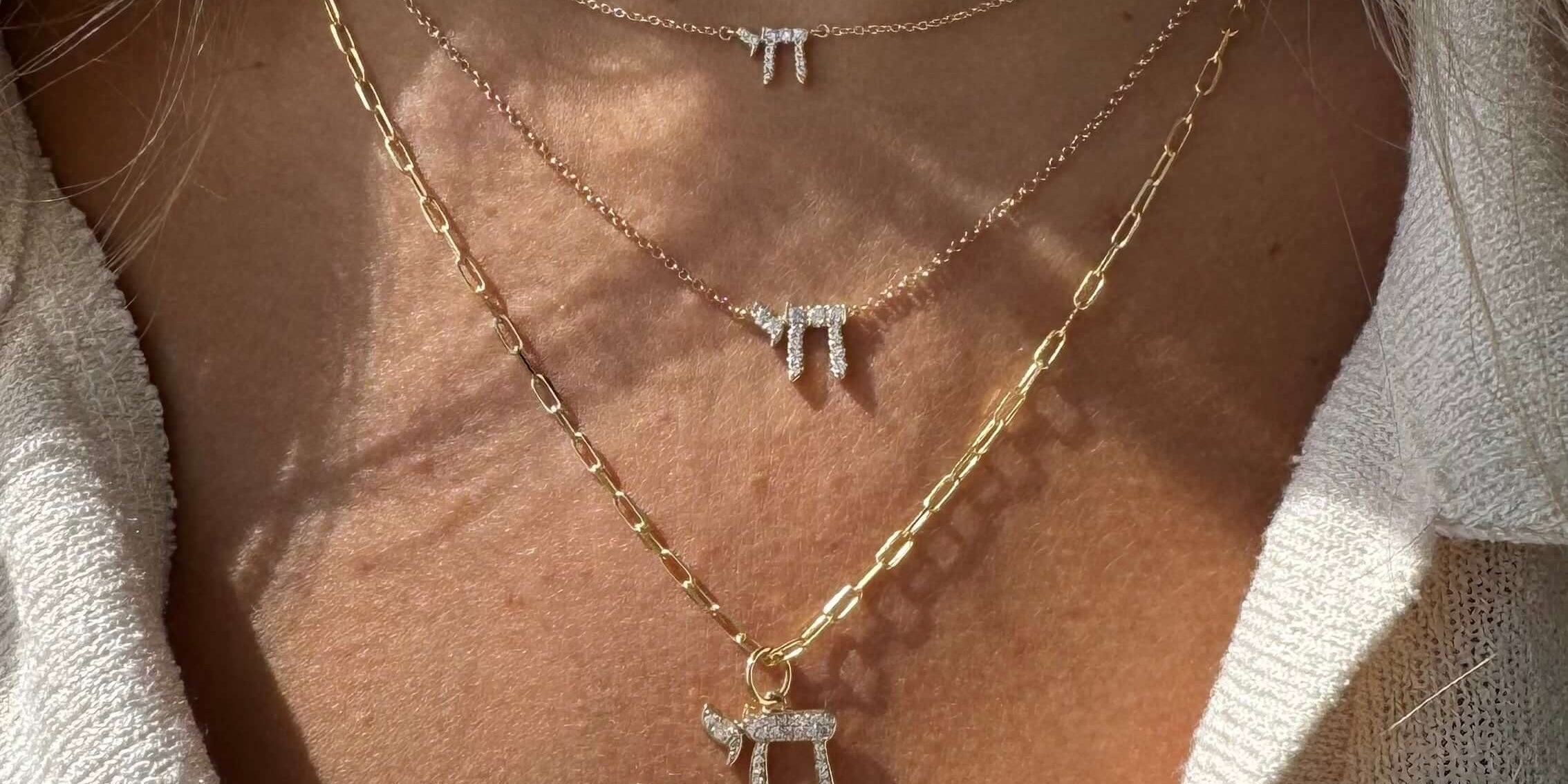 Layered gold and silver necklaces with unique pendant charms on a woman's neck, showcasing a stylish jewelry collection.