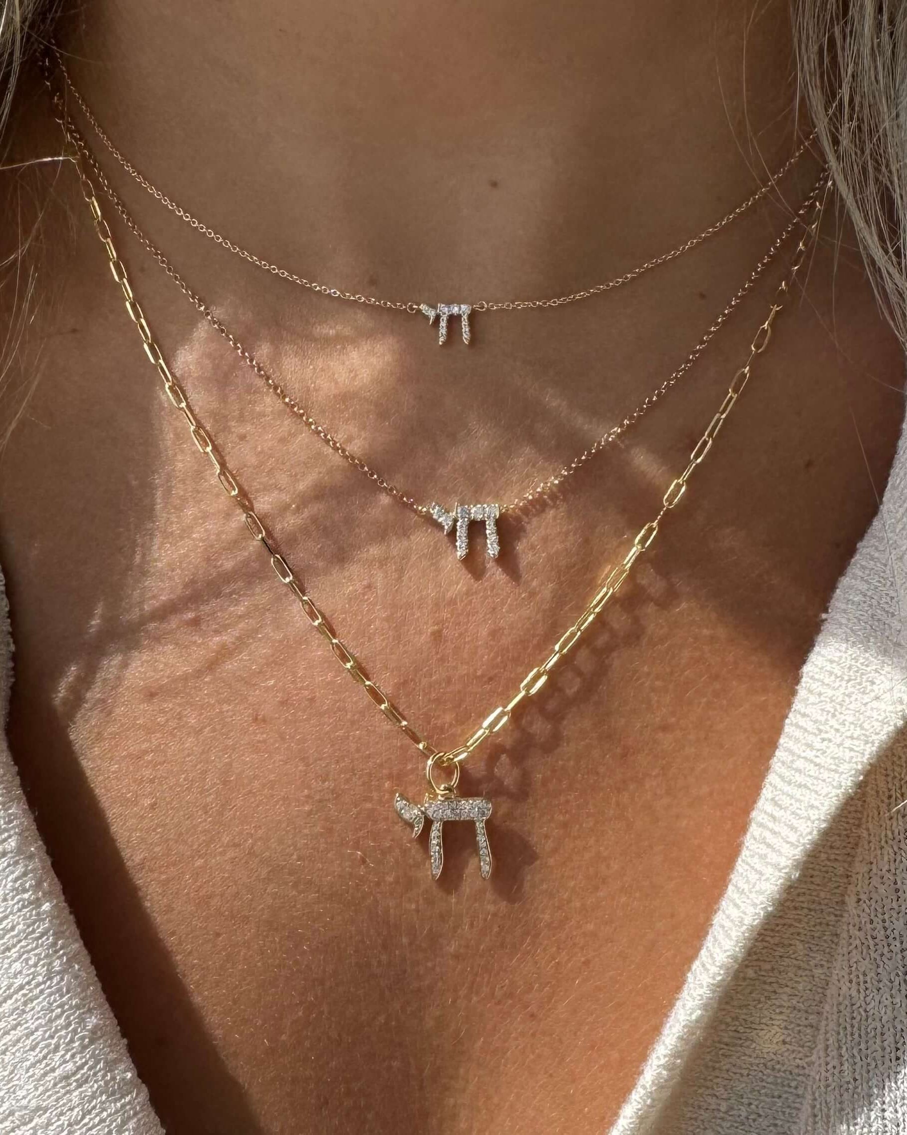 Layered gold and silver necklaces with unique pendant charms on a woman's neck, showcasing a stylish jewelry collection.