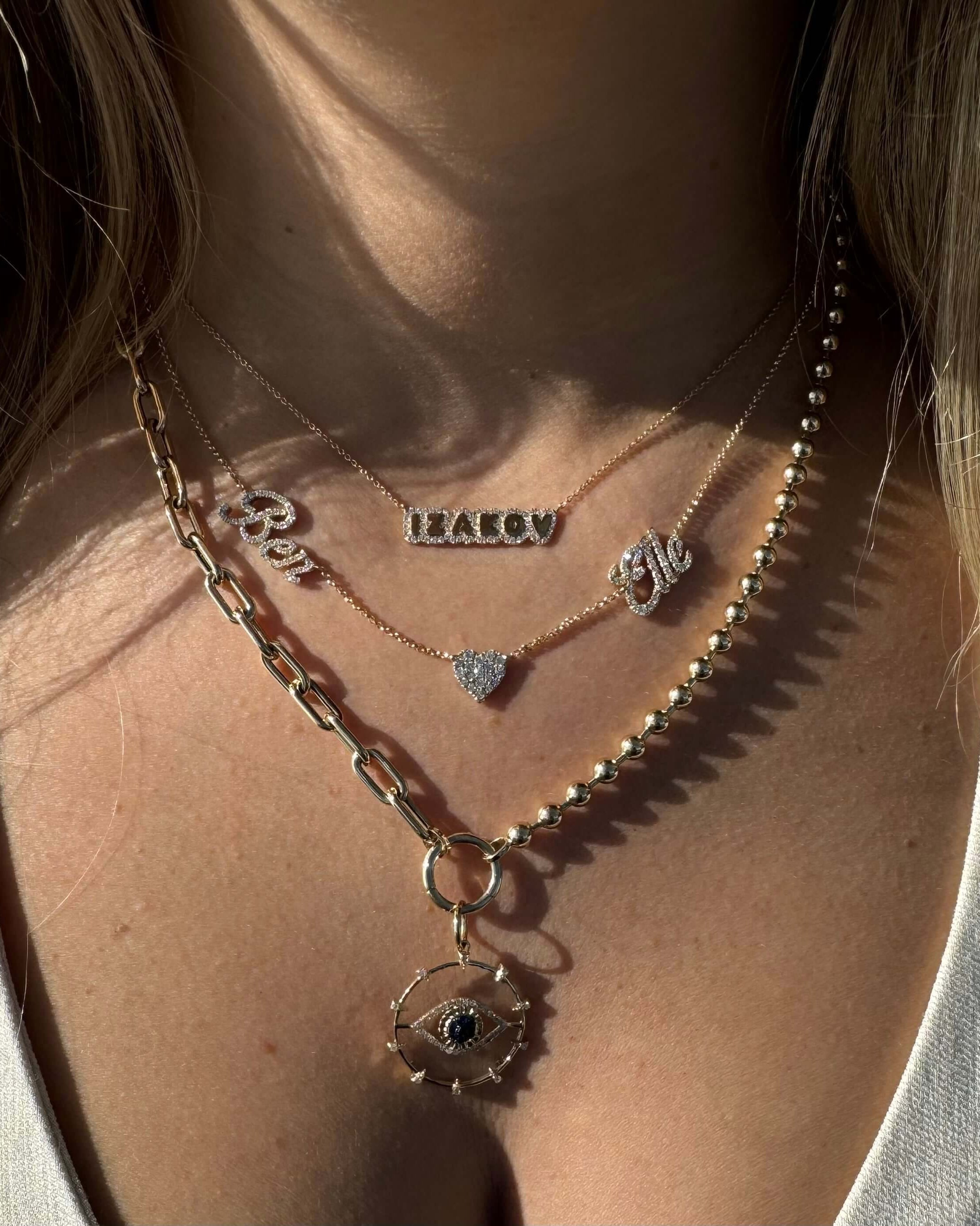 Trendy layered gold necklaces featuring personalized nameplates and a decorative charm, perfect for stylish accessorizing.