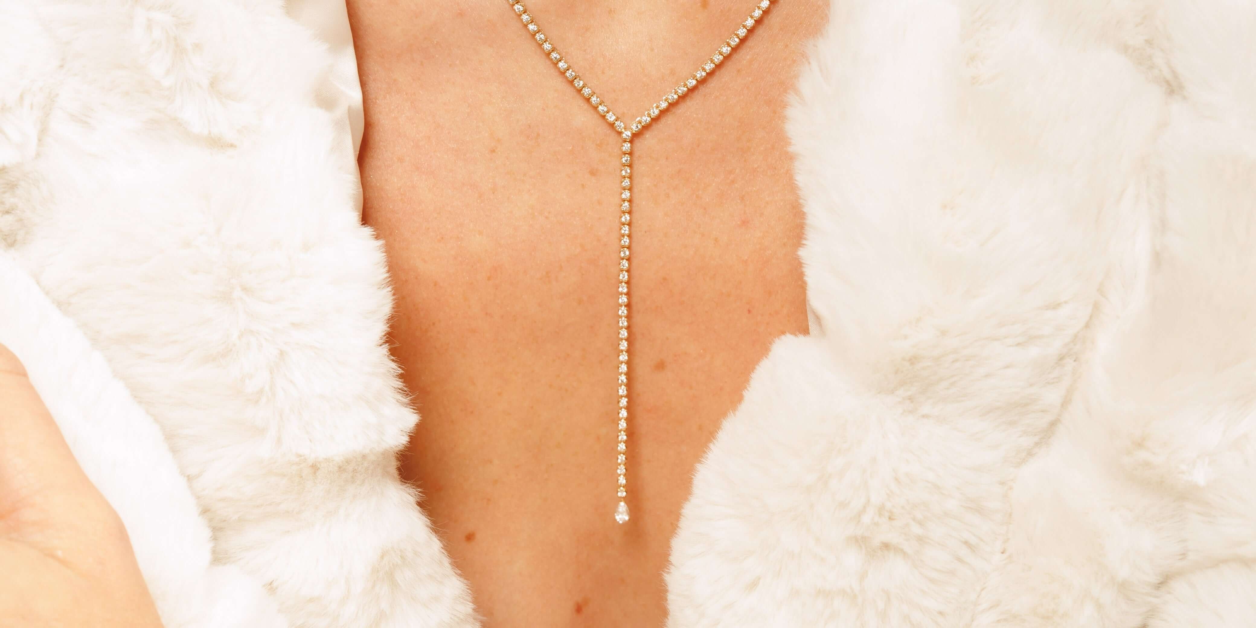Elegant tennis necklaces layered on a model's neck, showcasing sparkling details against a soft, white fur backdrop.