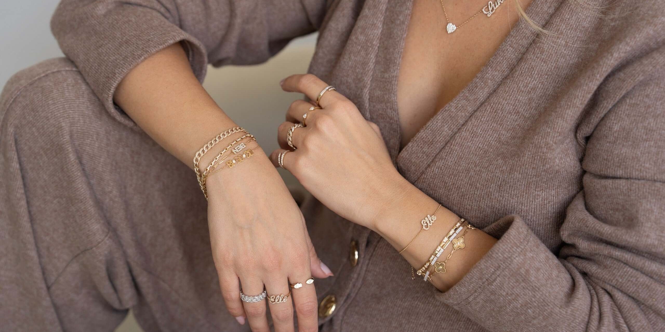 A close-up of personalized nameplates and jewelry worn on a woman's hands and neck.