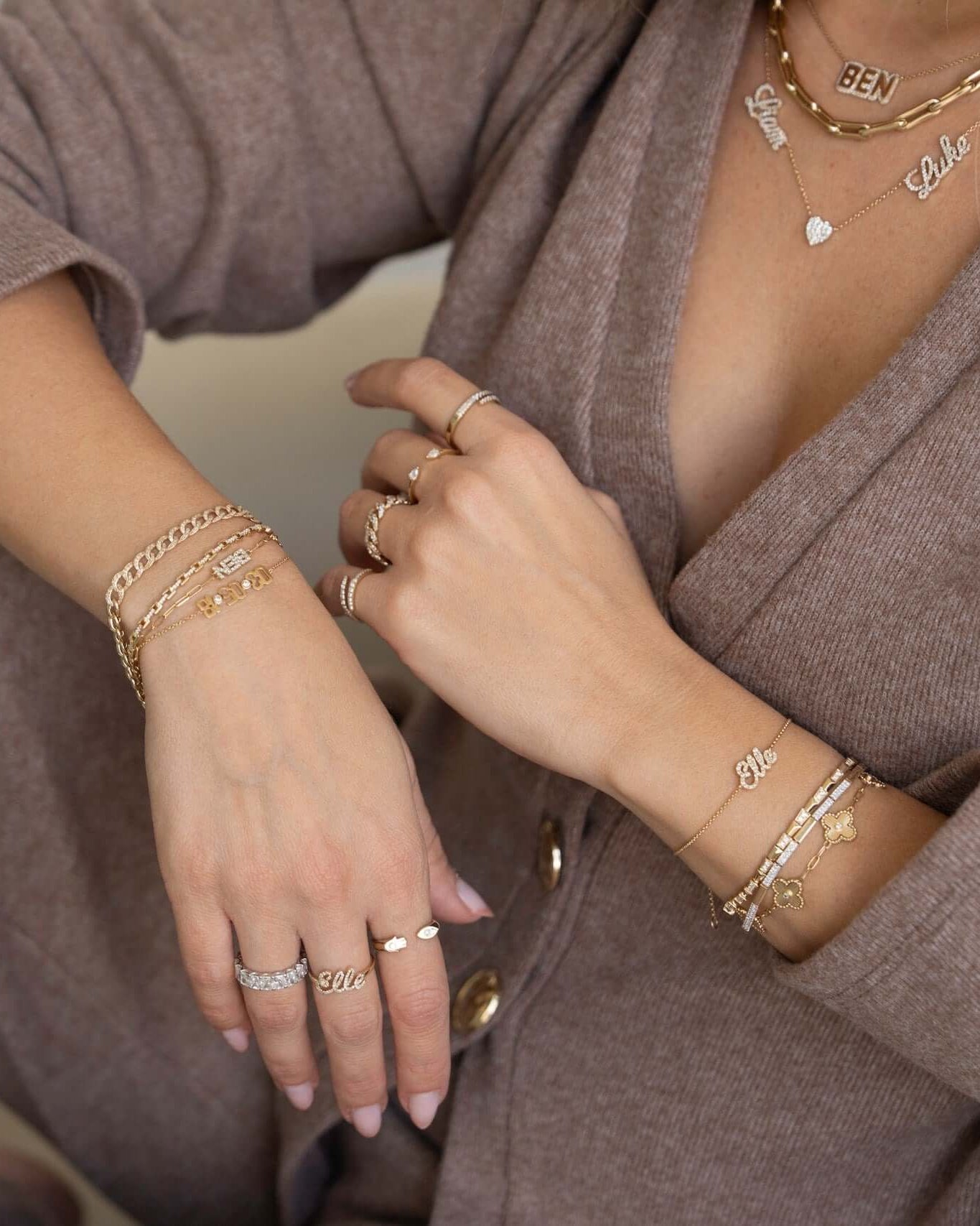 A close-up of personalized nameplates and jewelry worn on a woman's hands and neck.