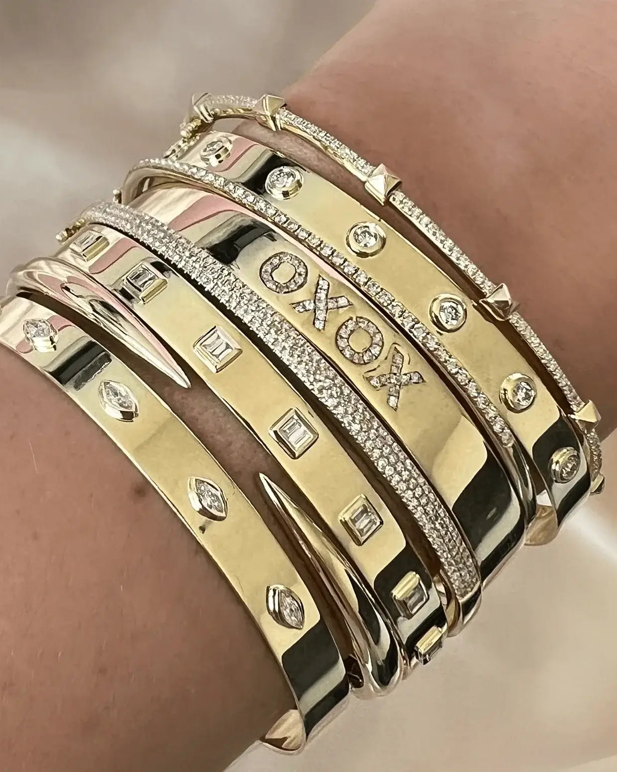 A collection of stylish gold bangle bracelets adorned with diamonds and unique designs on a wrist.
