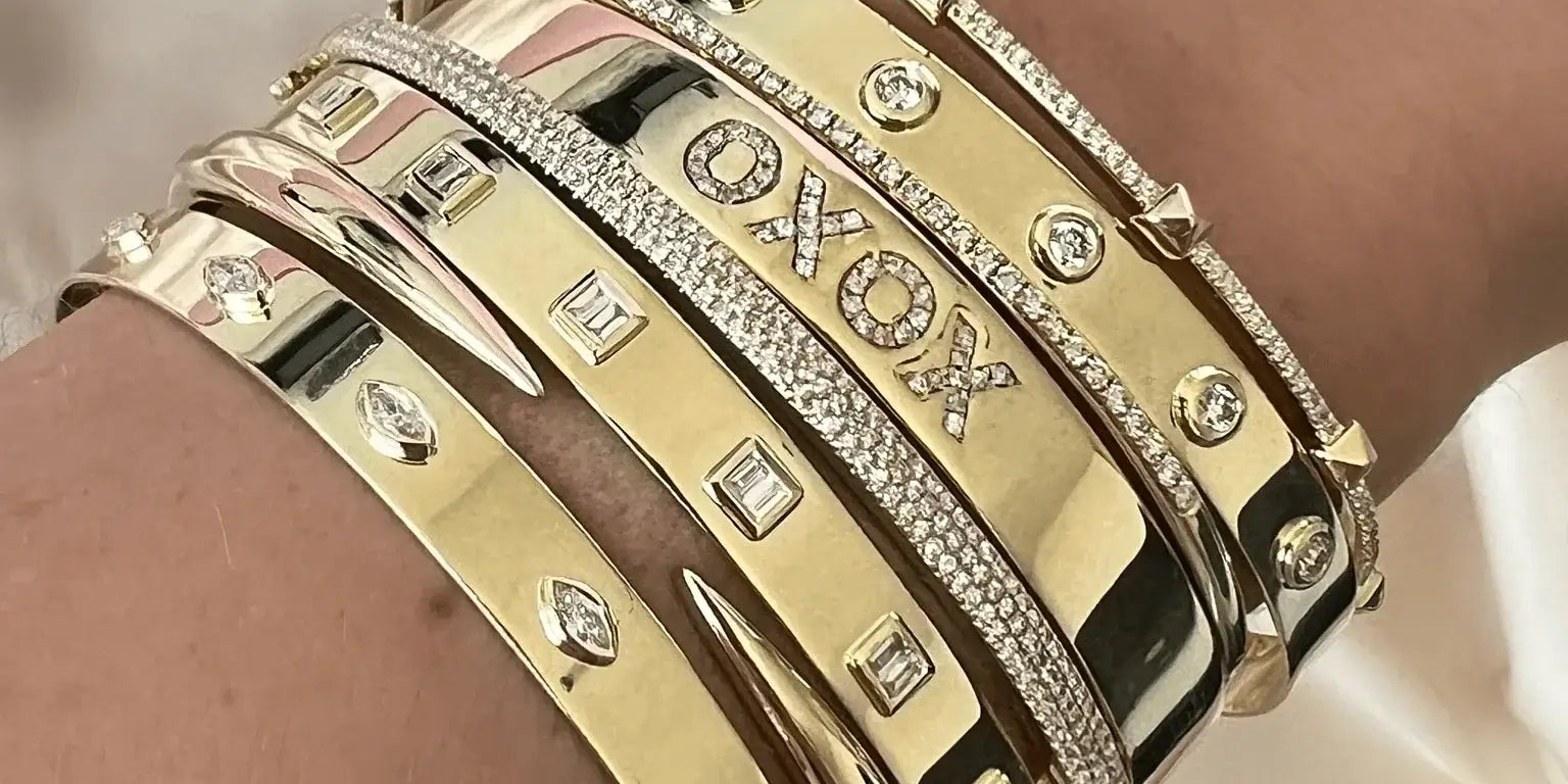 A collection of stylish gold bangle bracelets adorned with diamonds and unique designs on a wrist.