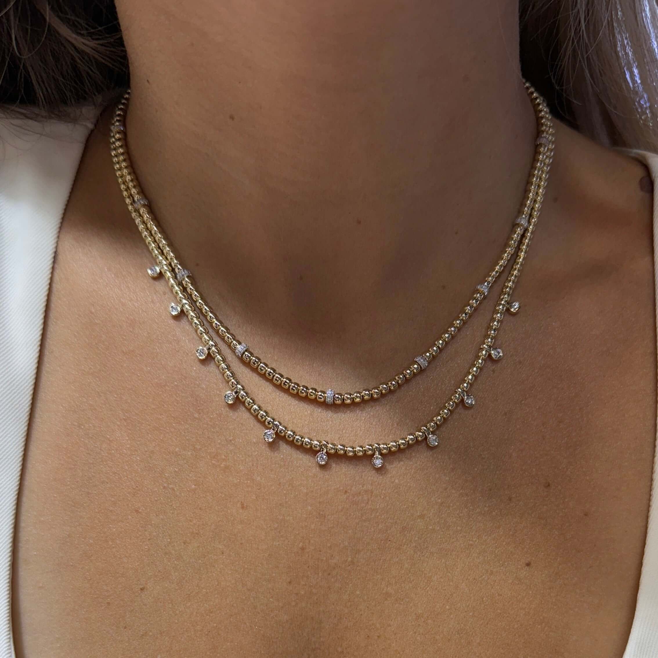 Necklace on a person wearing a white top with a button detail.