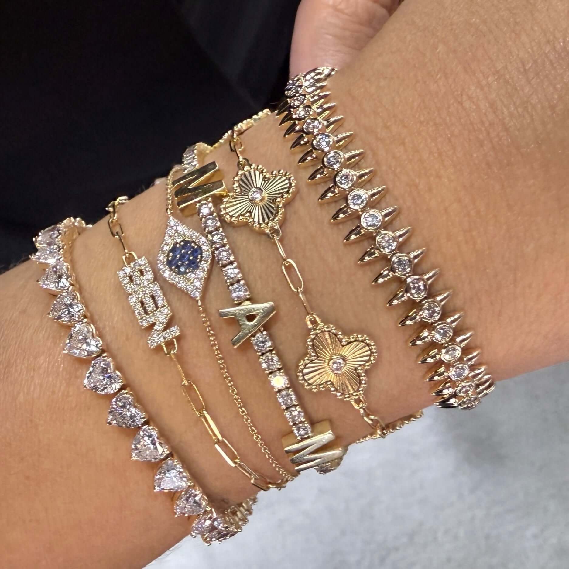 Multiple gold and diamond bracelets elegantly worn on a wrist, showcasing various designs and sparkle.