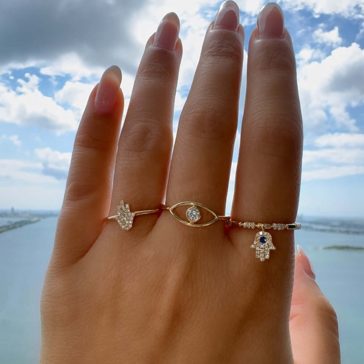 Dangling Hamsa Diamond Ring showcased on a hand against a scenic backdrop, part of Izakov Fine Jewelry collection.