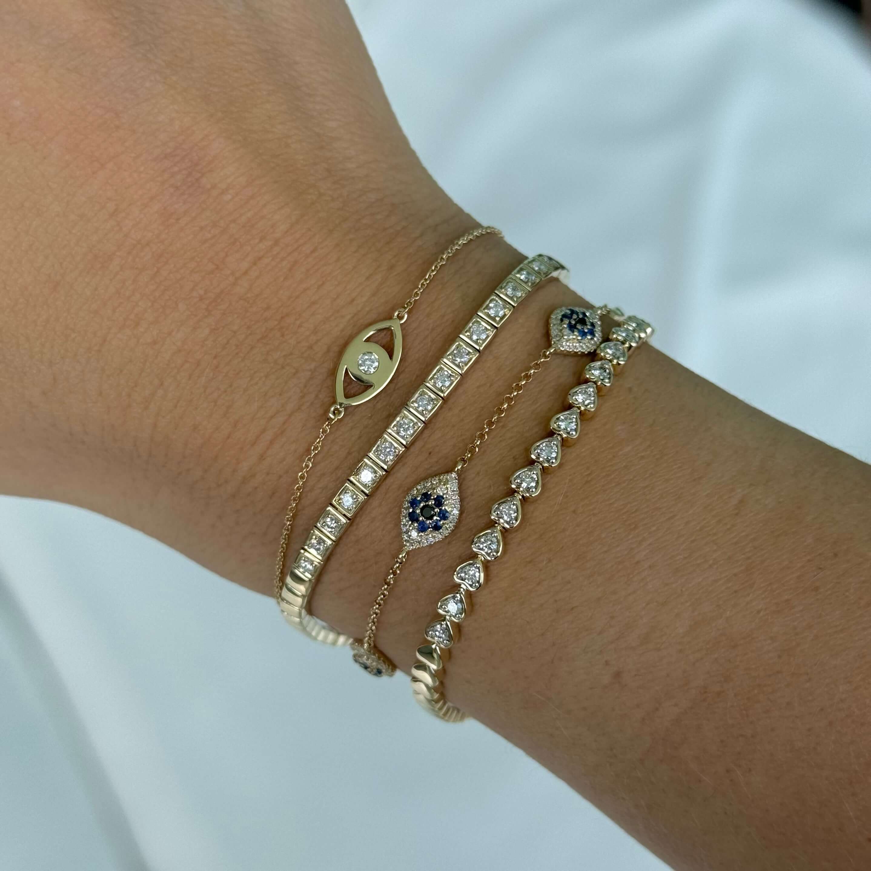 14K gold diamond accented evil eye bracelet worn on wrist, showcasing elegant design and luxurious gemstones.