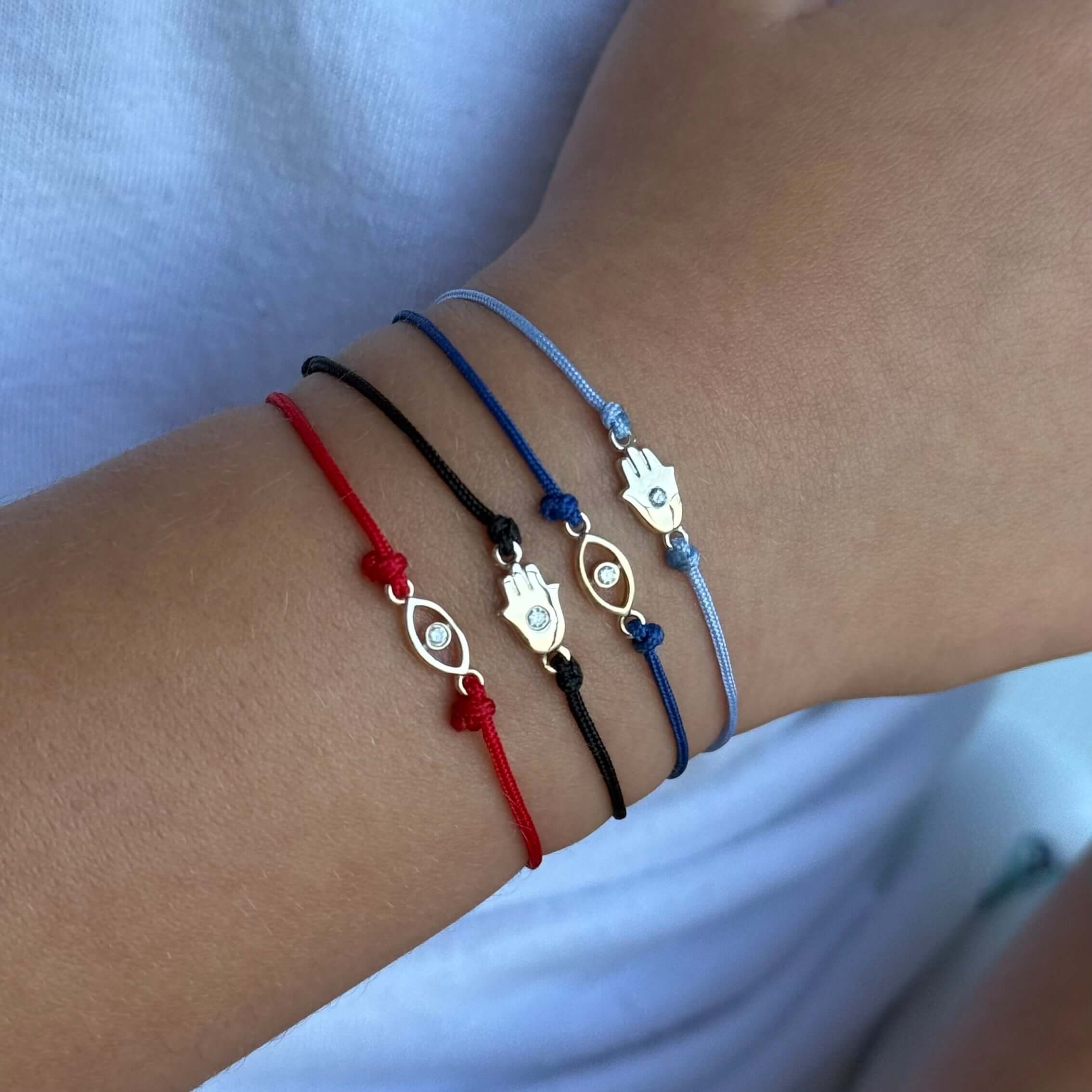 Colorful cord bracelets featuring evil eye and hamsa charms, perfect for adding protection and style to any outfit.