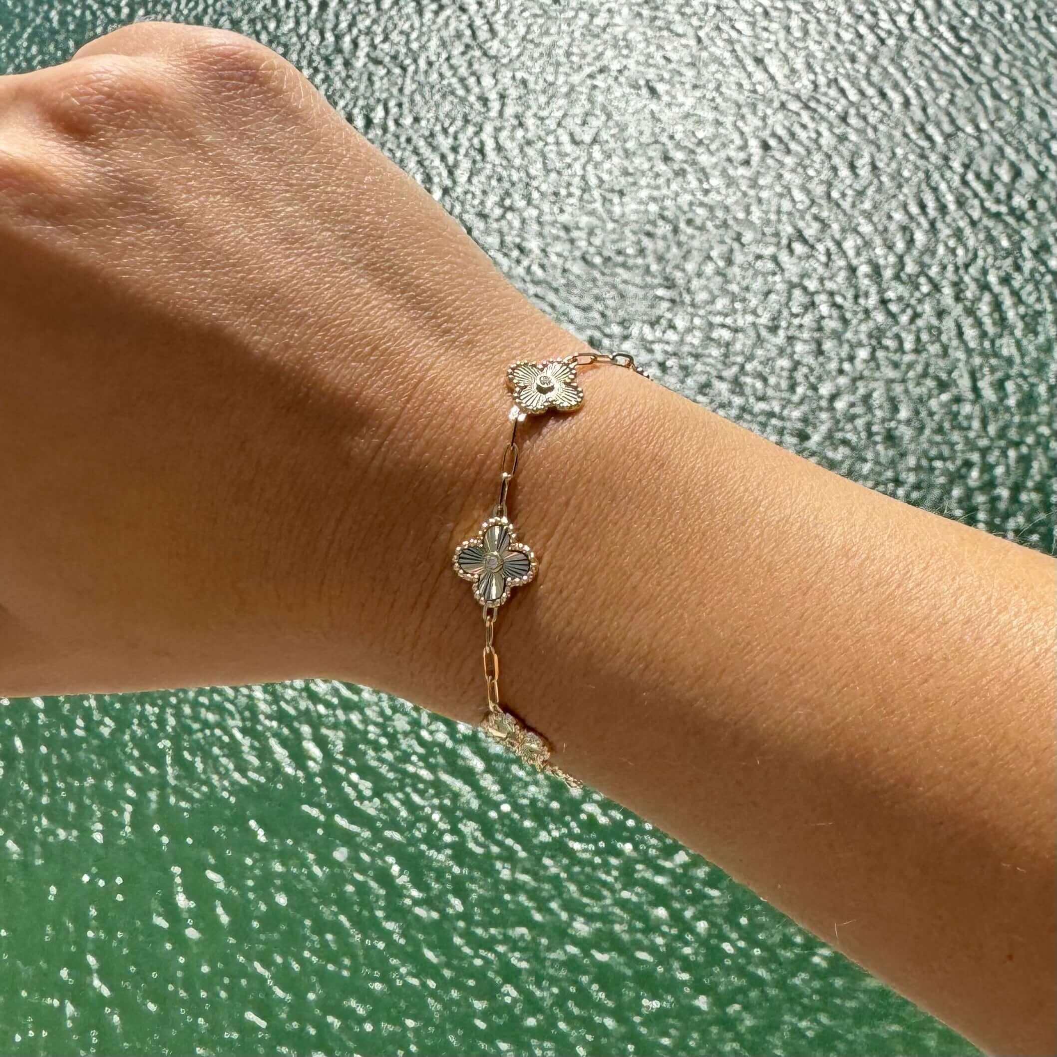 Elegant four-leaf clover bracelet in gold on wrist, our jewelry design with shimmering details.