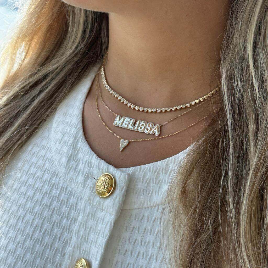 Woman wearing layered gold necklaces with personalized 'Melissa' name pendant from our jewelry brand.