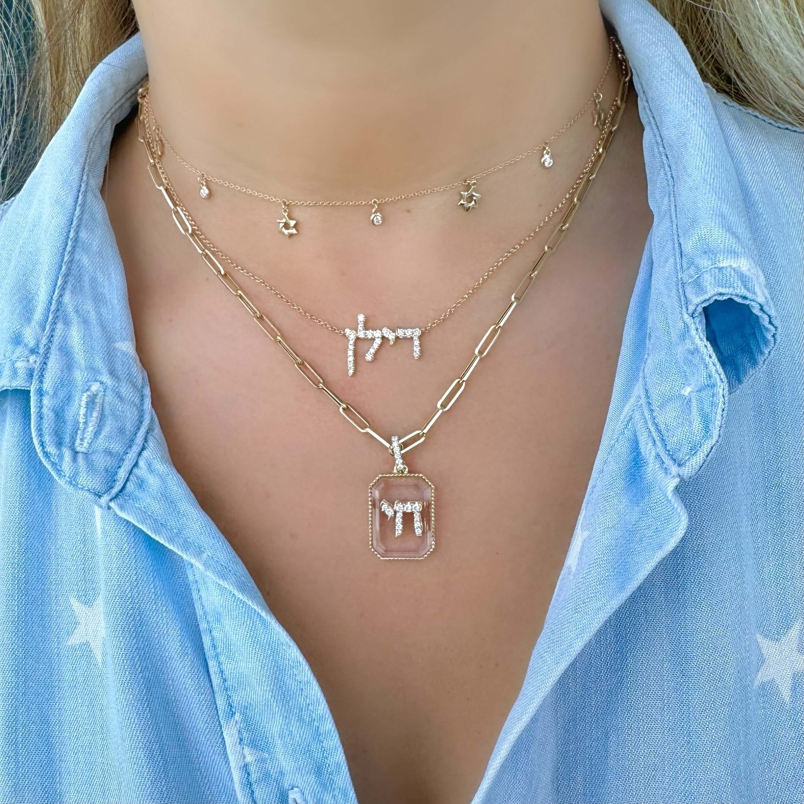Model wearing layered necklaces showcasing a 14K Gold Diamond Chai On Crystal Pendant and dainty gold chains.