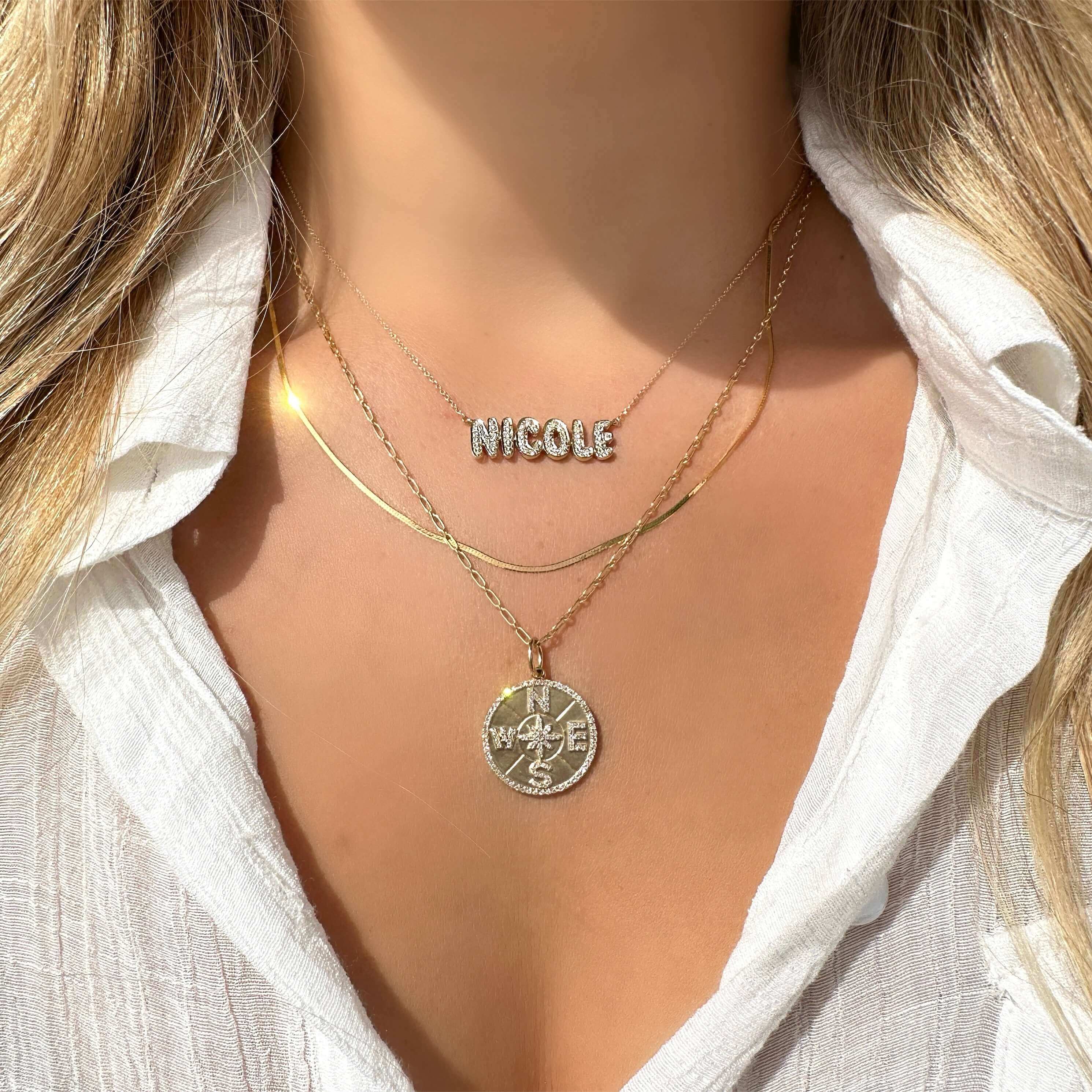 Woman wearing layered necklaces with personalized "Nicole" nameplate and pendant from our jewelry collection.