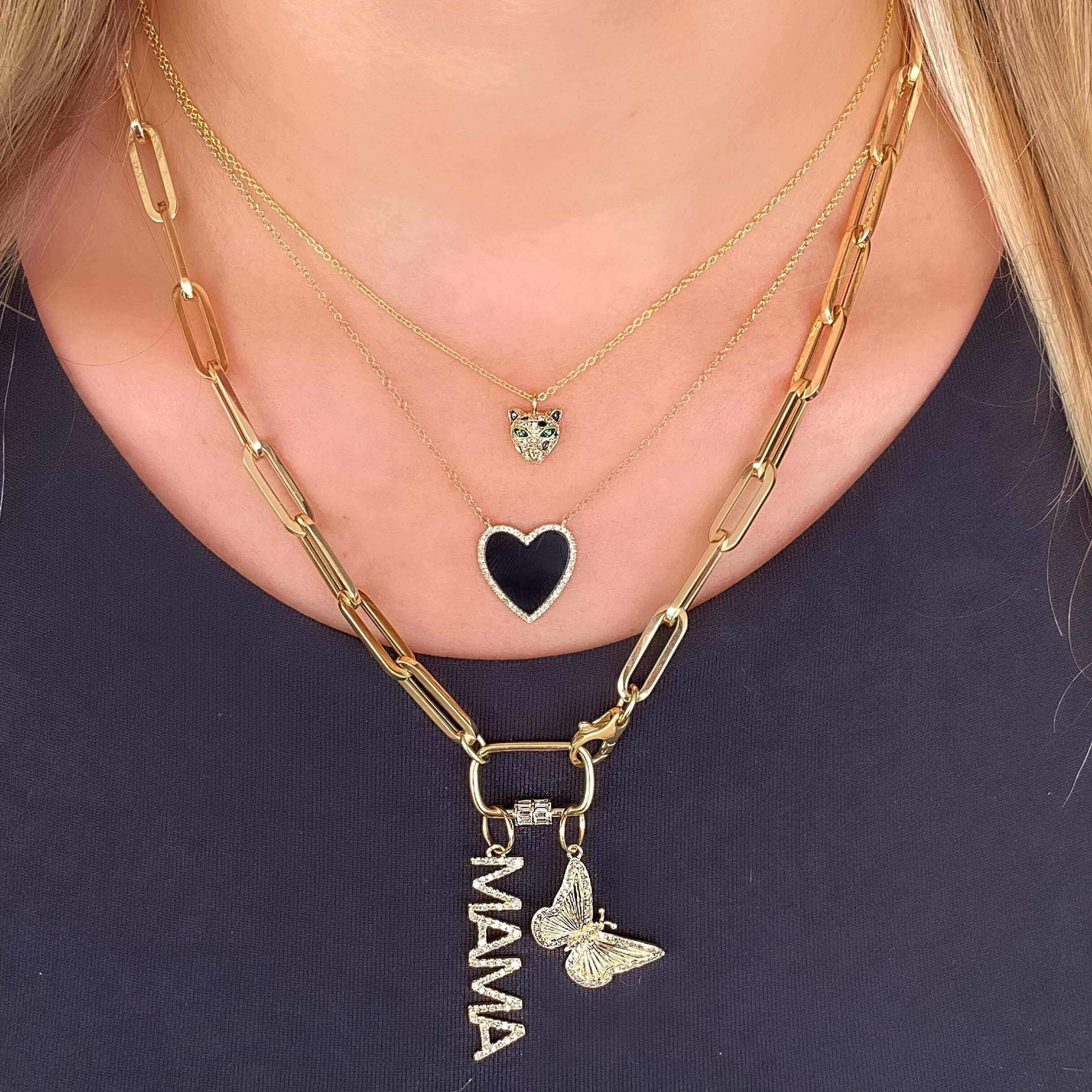 Woman wearing layered gold necklaces with heart and butterfly charms from our jewelry collection.