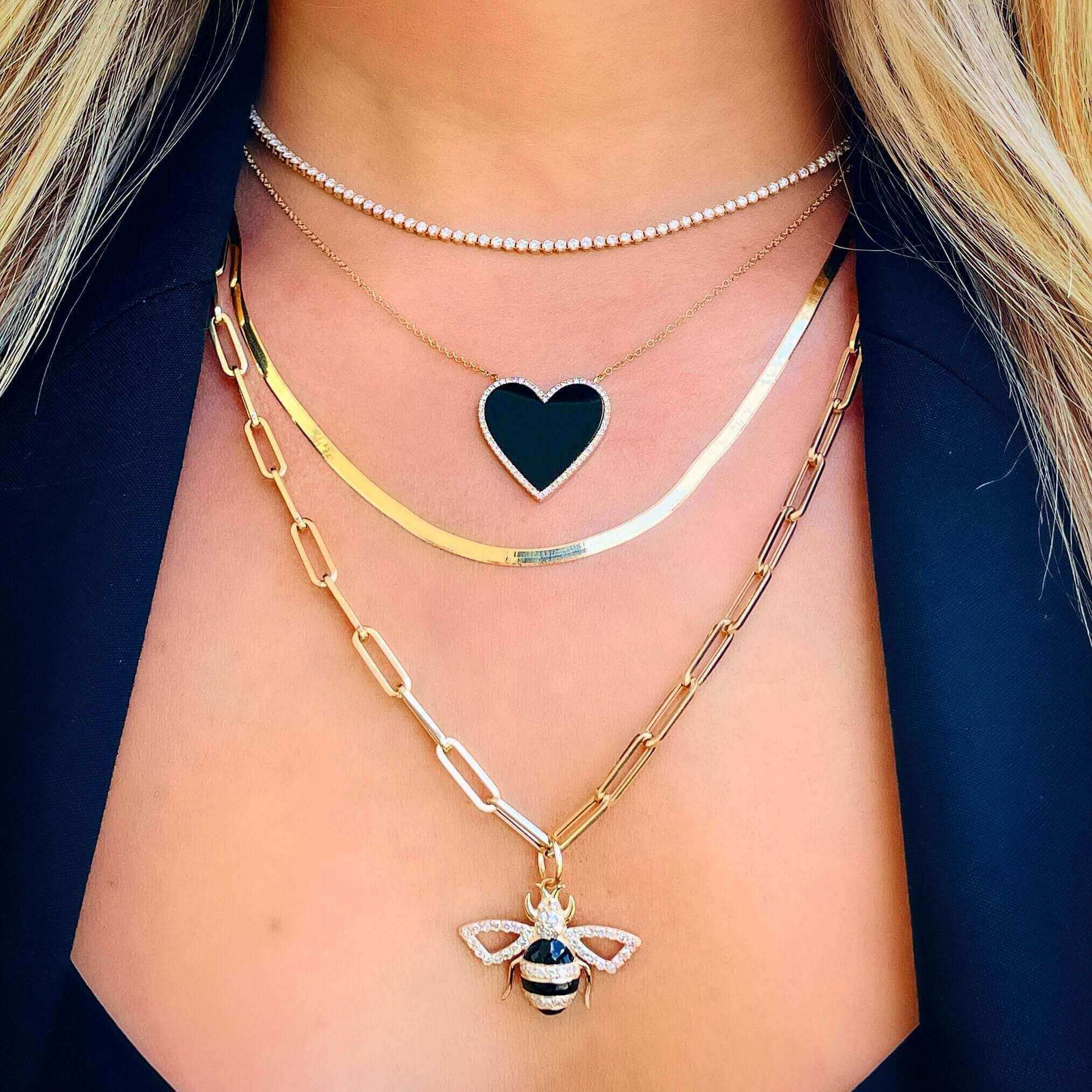Layered necklaces with heart and bee pendants in focus, enhancing a stylish and luxurious jewelry look.