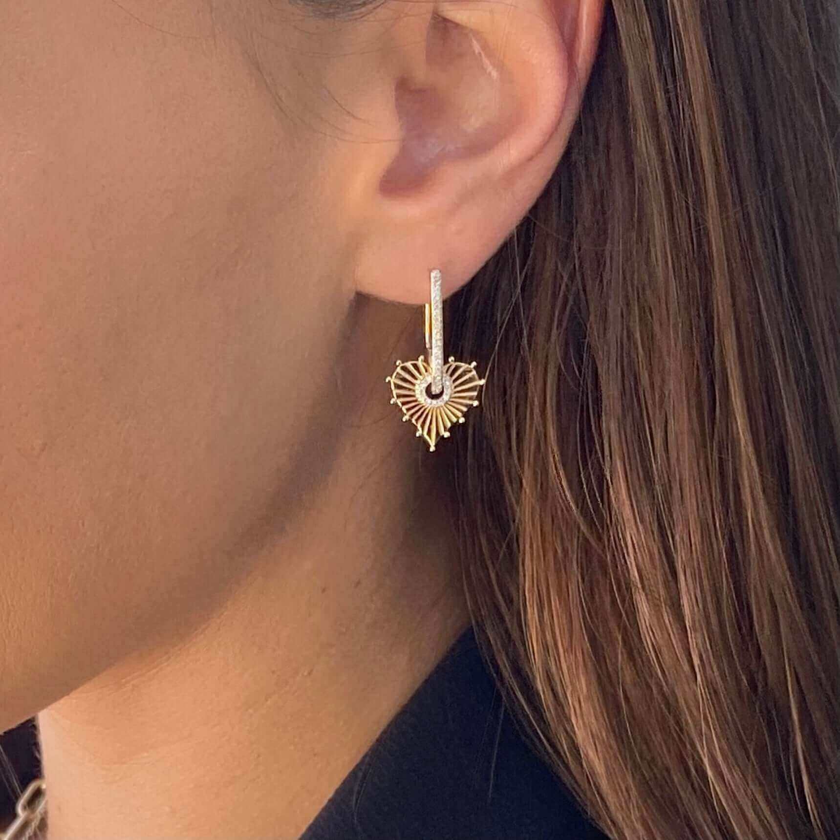 Close-up of a woman's ear wearing a stylish gold heart-shaped earring from our jewelry collection.