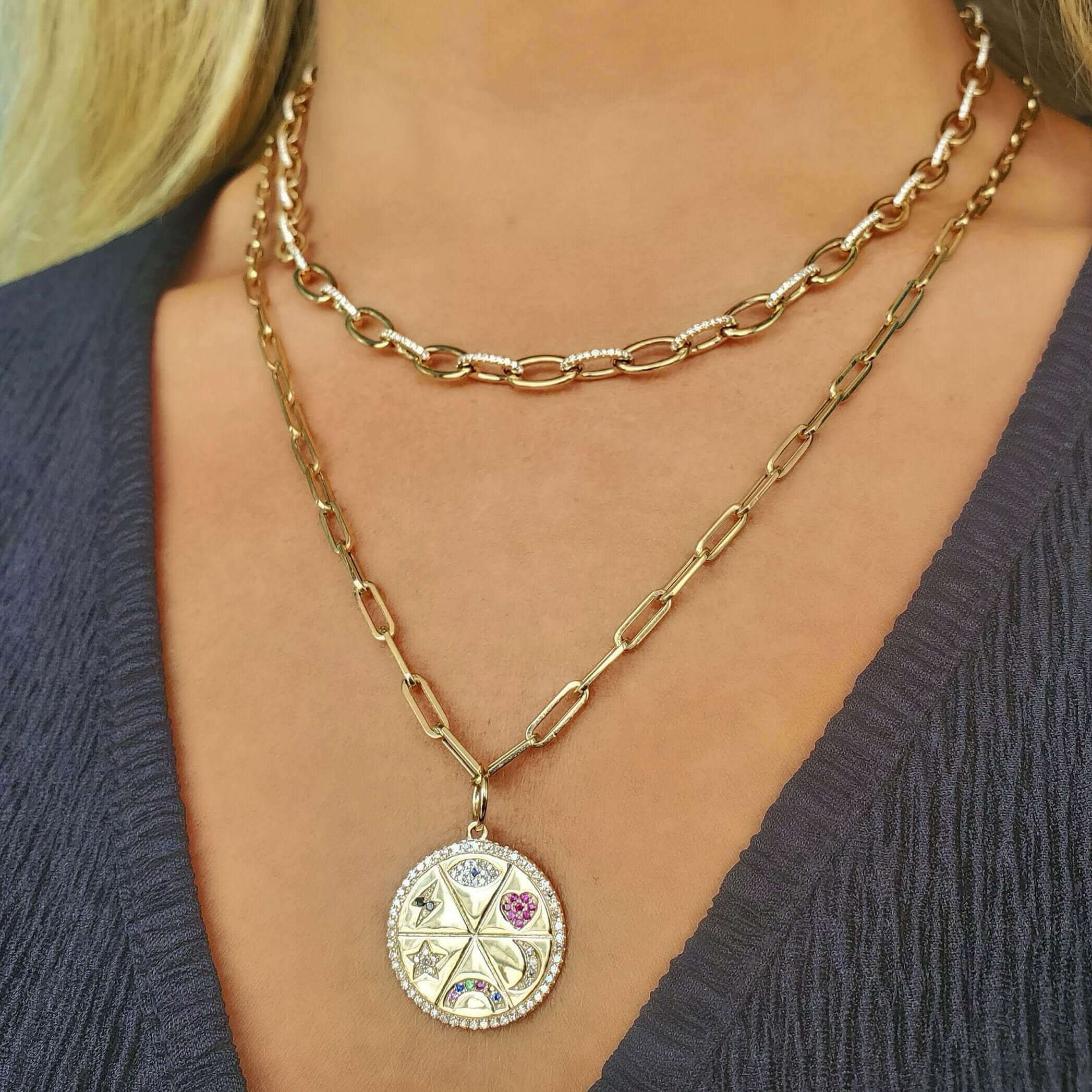 Woman wearing layered gold necklaces featuring a medallion with gemstones from our elegant jewelry collection.