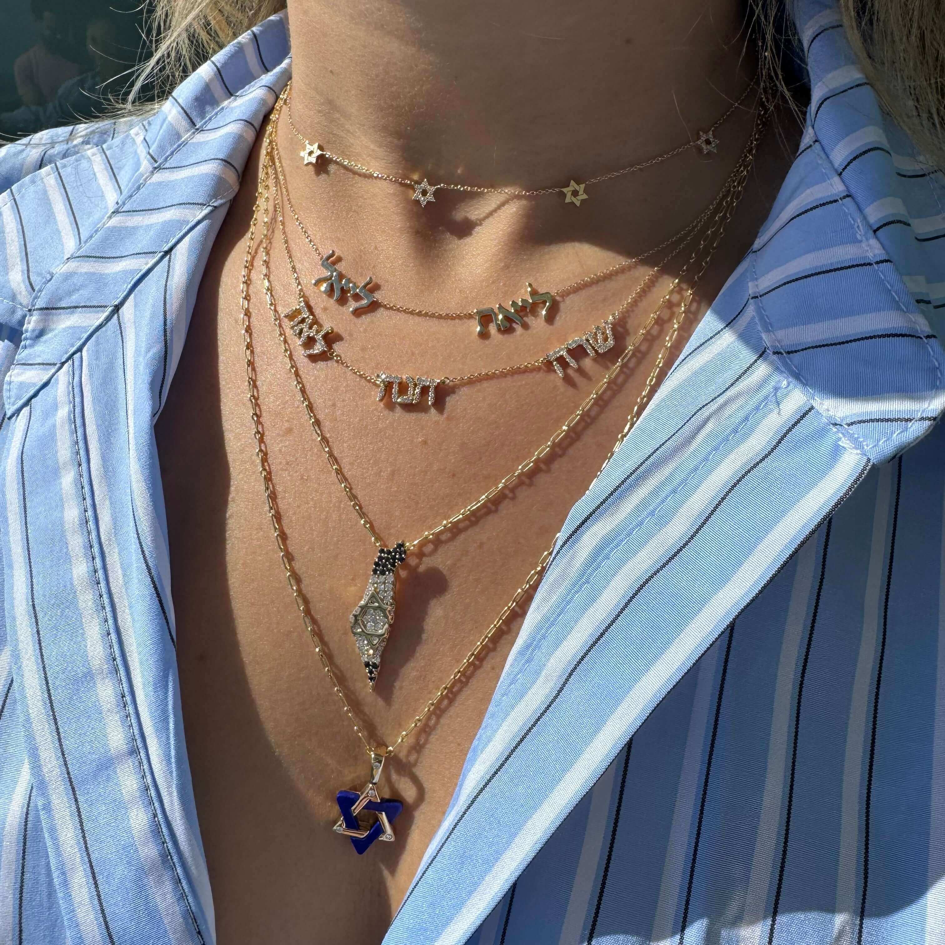 Woman wearing layered gold necklaces with Hebrew letters and a Star of David pendant from our jewelry collection.