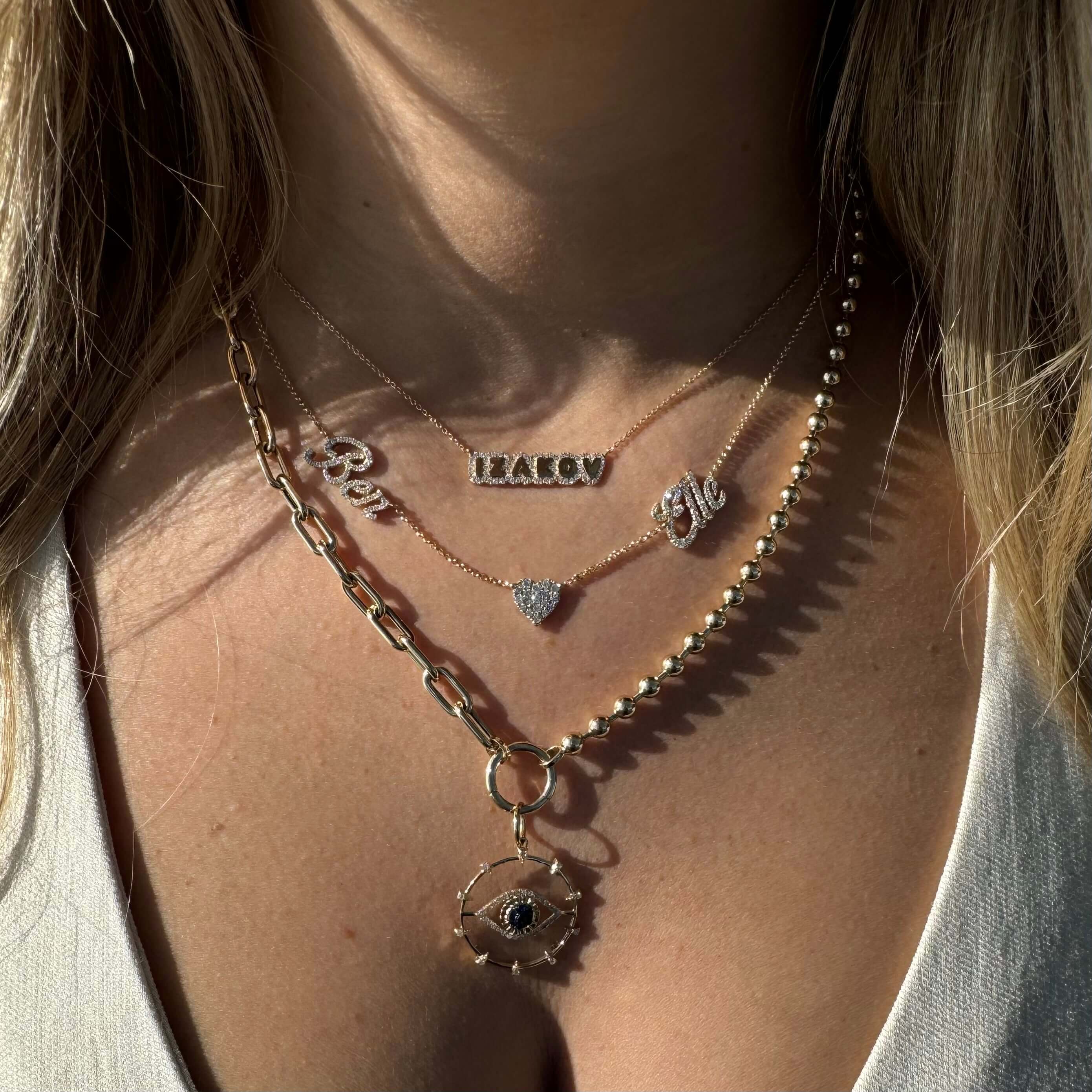 Close-up of layered gold necklaces featuring charms and pendants on a woman's neck.