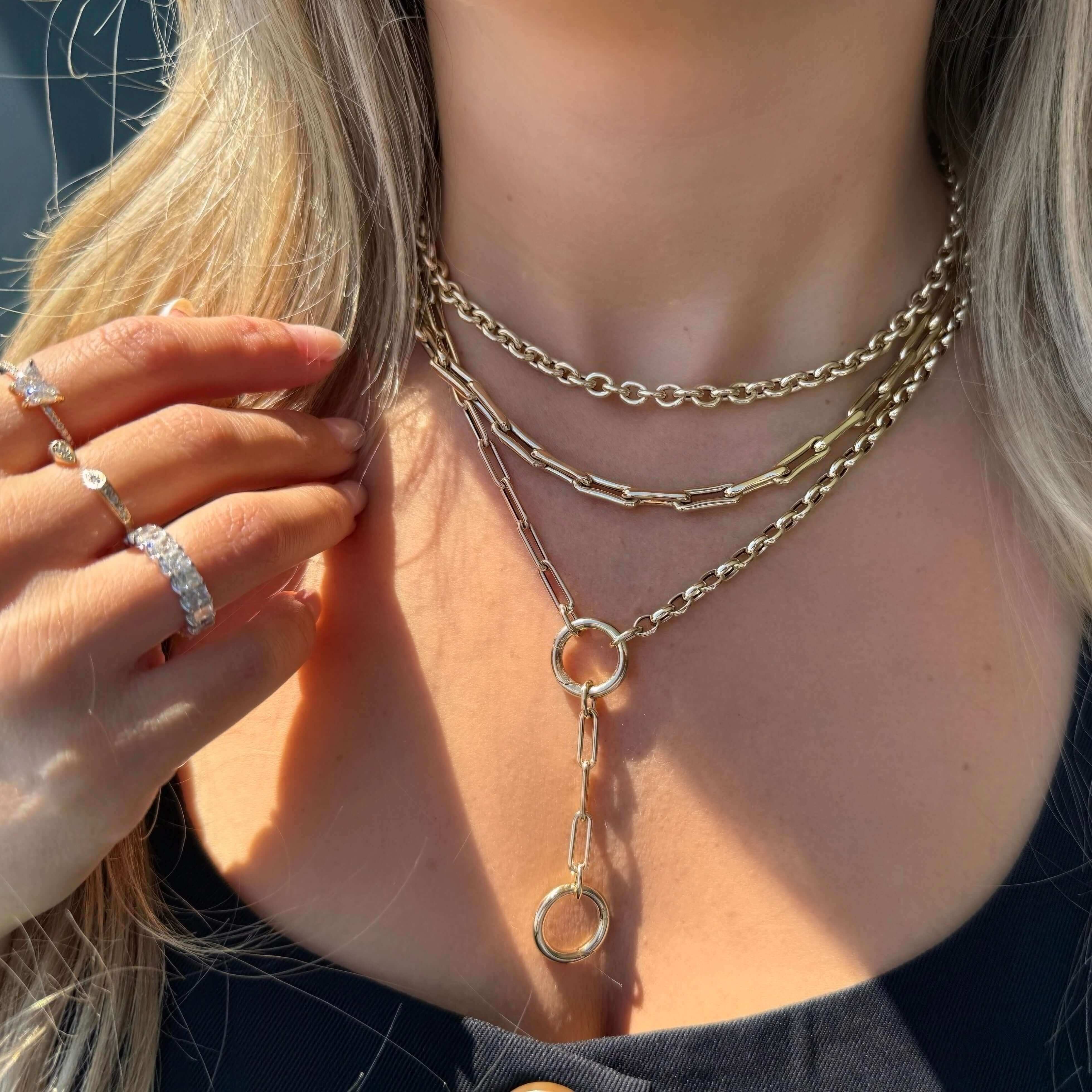 Model showcasing layered 14K gold chunky cable link necklaces and a ring, highlighting elegant jewelry style.
