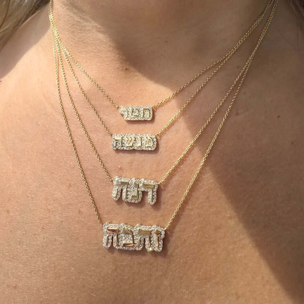 Gold layered necklaces with Hebrew script pendants adorned with sparkling diamonds from our exclusive jewelry collection.