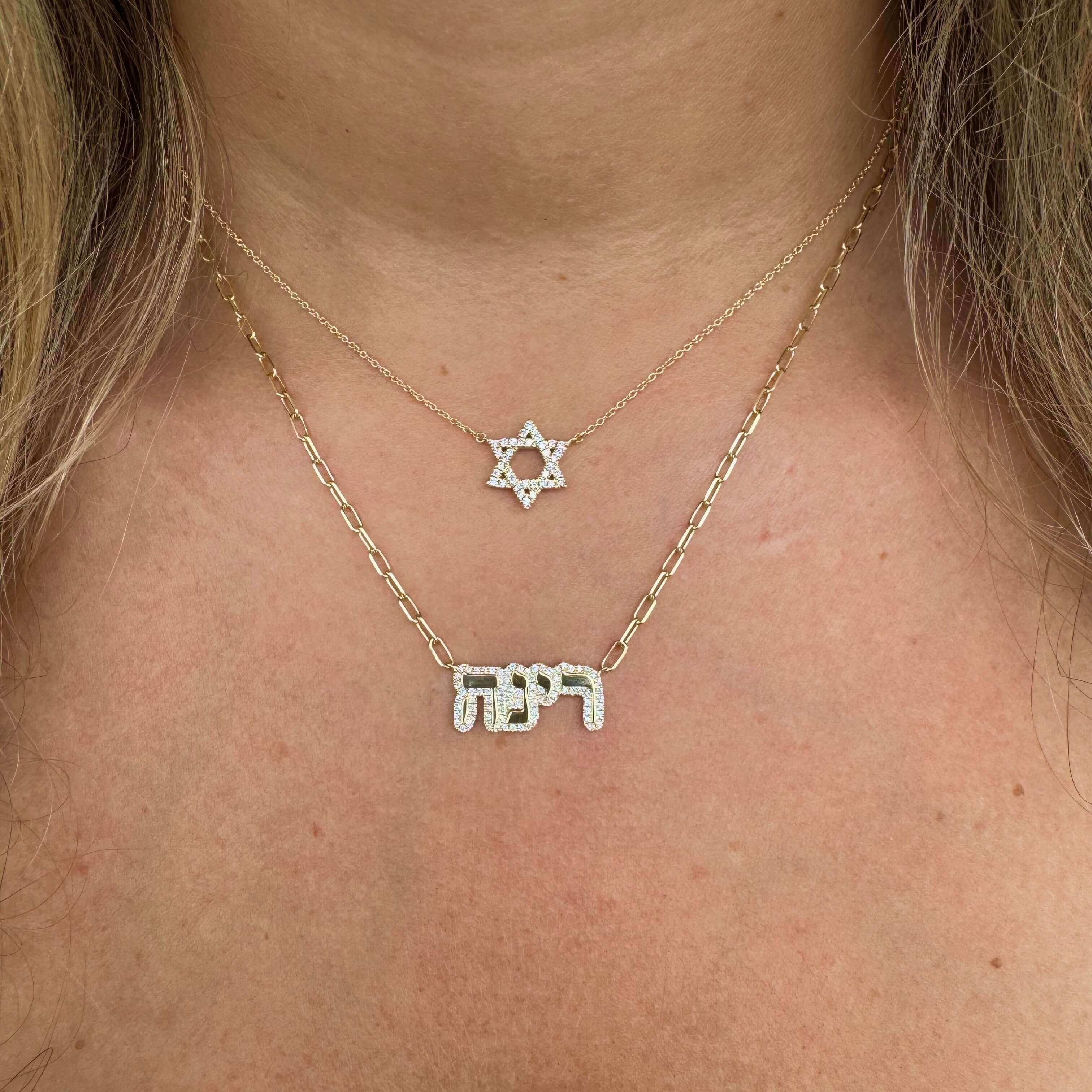 Woman wearing gold star of David necklace with Hebrew name pendant necklace, showcasing unique jewelry brand style.