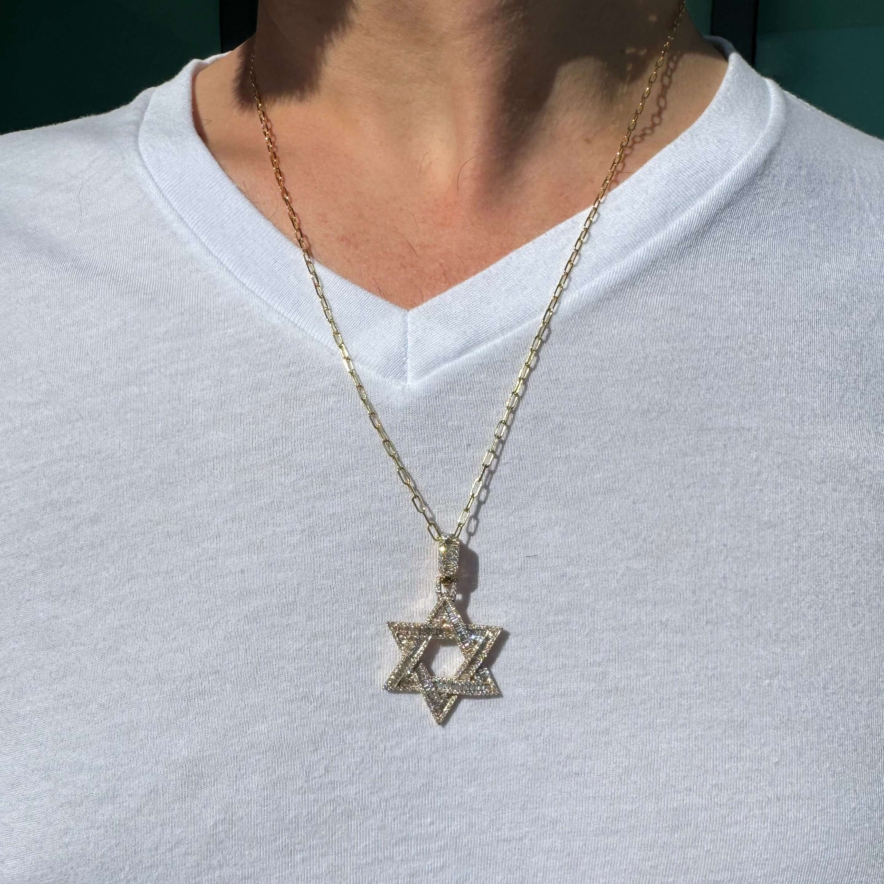 Close-up of a person wearing a 14K Gold Iced Baguette Diamond Star of David Pendant on a chain.