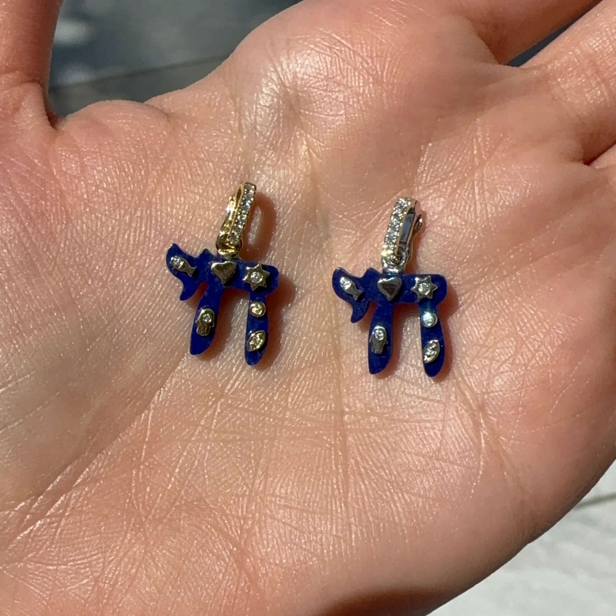 14K Gold Jewish Charms Chai Gemstone Pendant © displayed in a hand, featuring blue enamel with diamond accents.