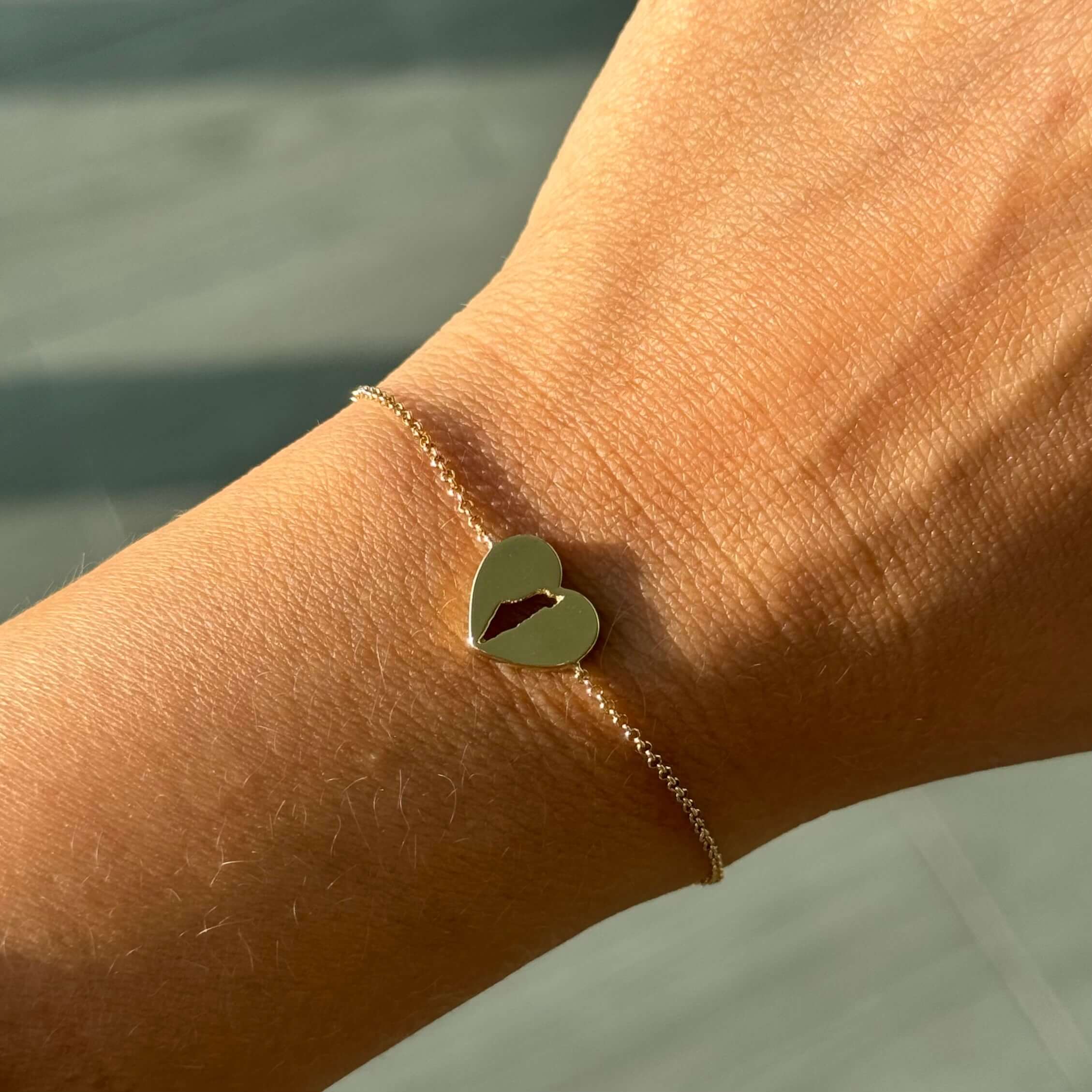 14K gold land of Israel cutout heart bracelet on wrist, symbolizing love and unity.