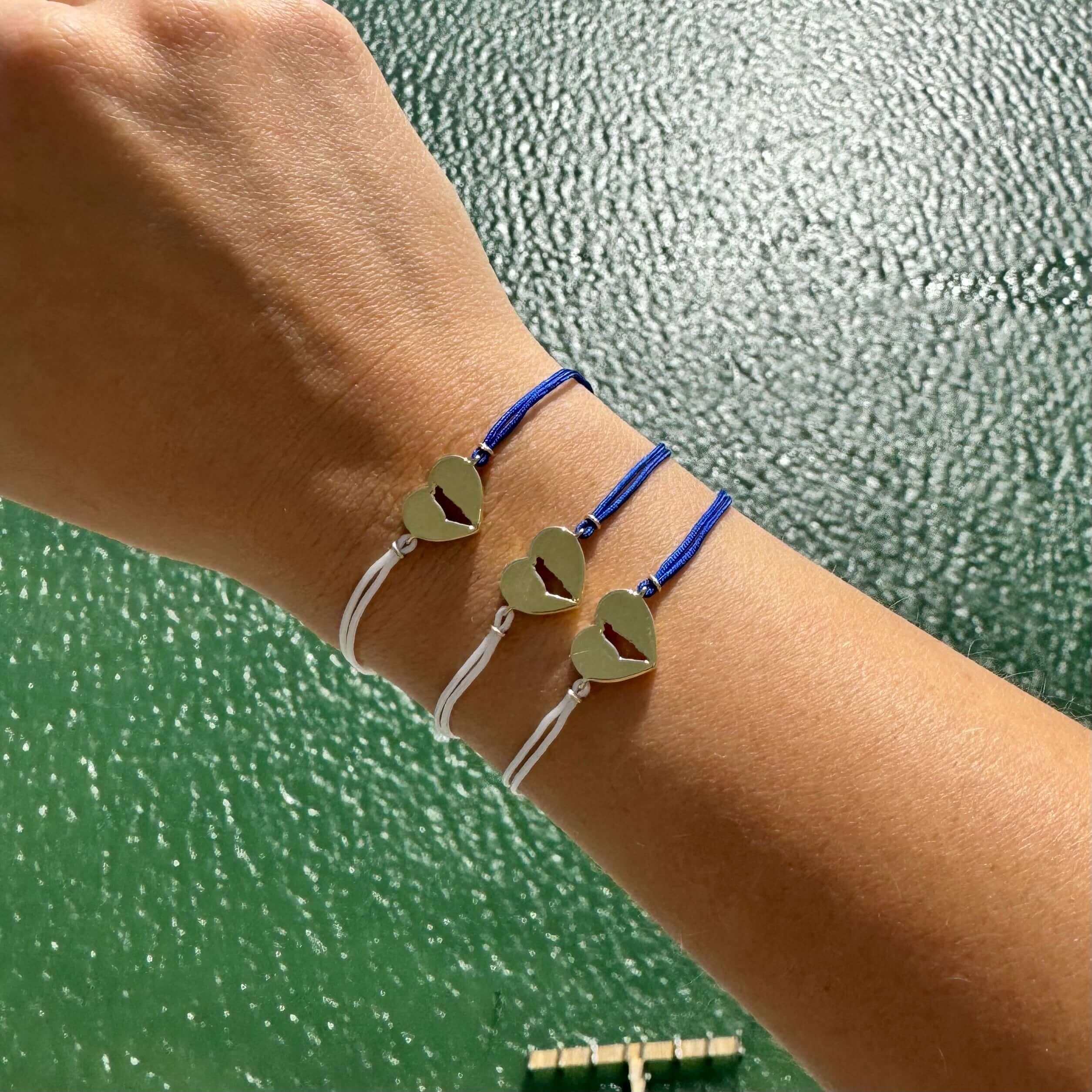 Stunning heart-shaped charm bracelets on wrist over green background, exclusive jewelry collection by our brand