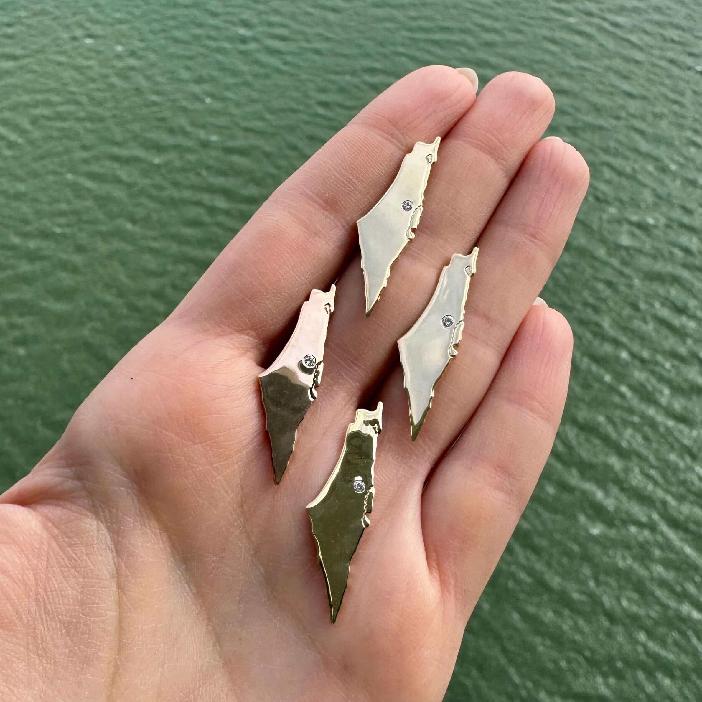 Hand holding unique gold earrings with gemstone accents from our luxury jewelry collection