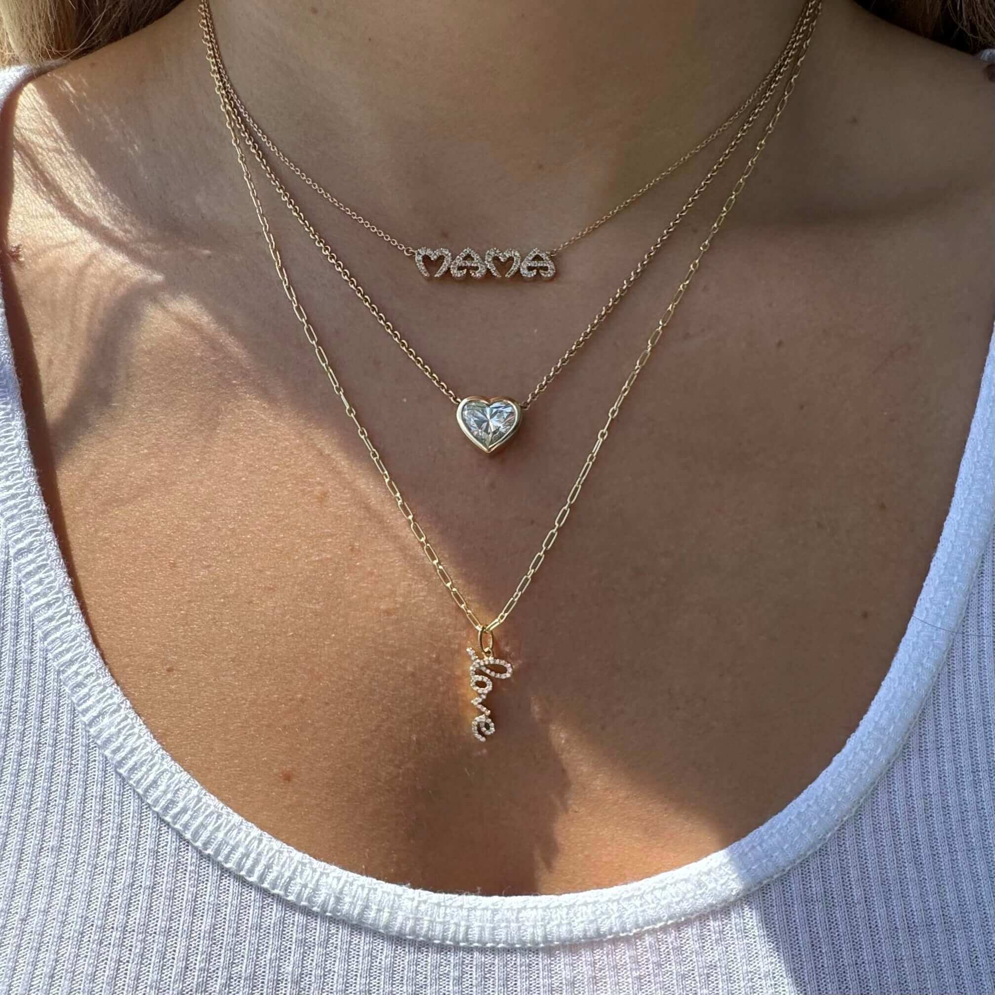 Woman wearing layered gold necklaces featuring "mama," heart, and love pendants from our jewelry brand.