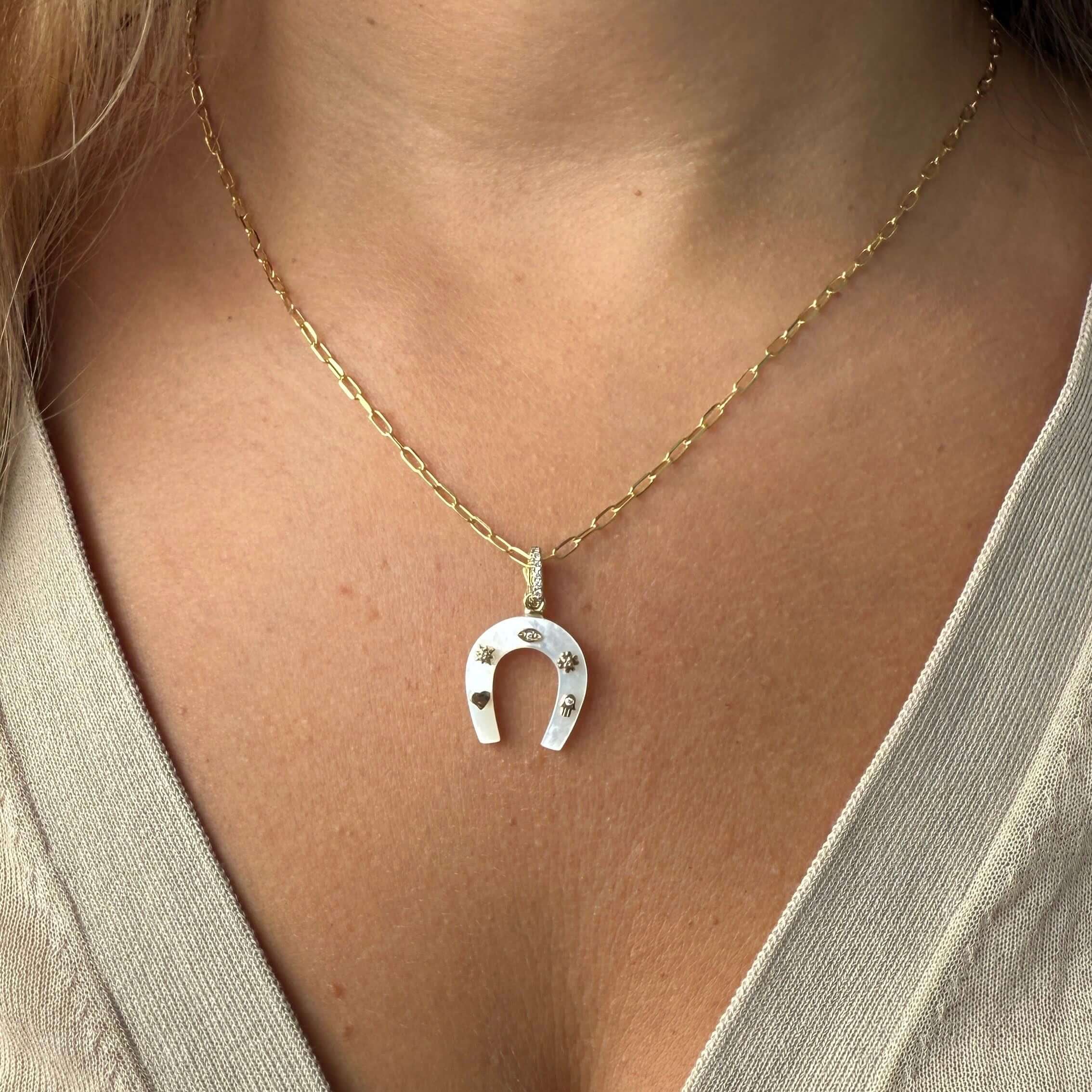 14K gold horseshoe gemstone pendant on a delicate chain, featuring diamond accents and lucky symbols.