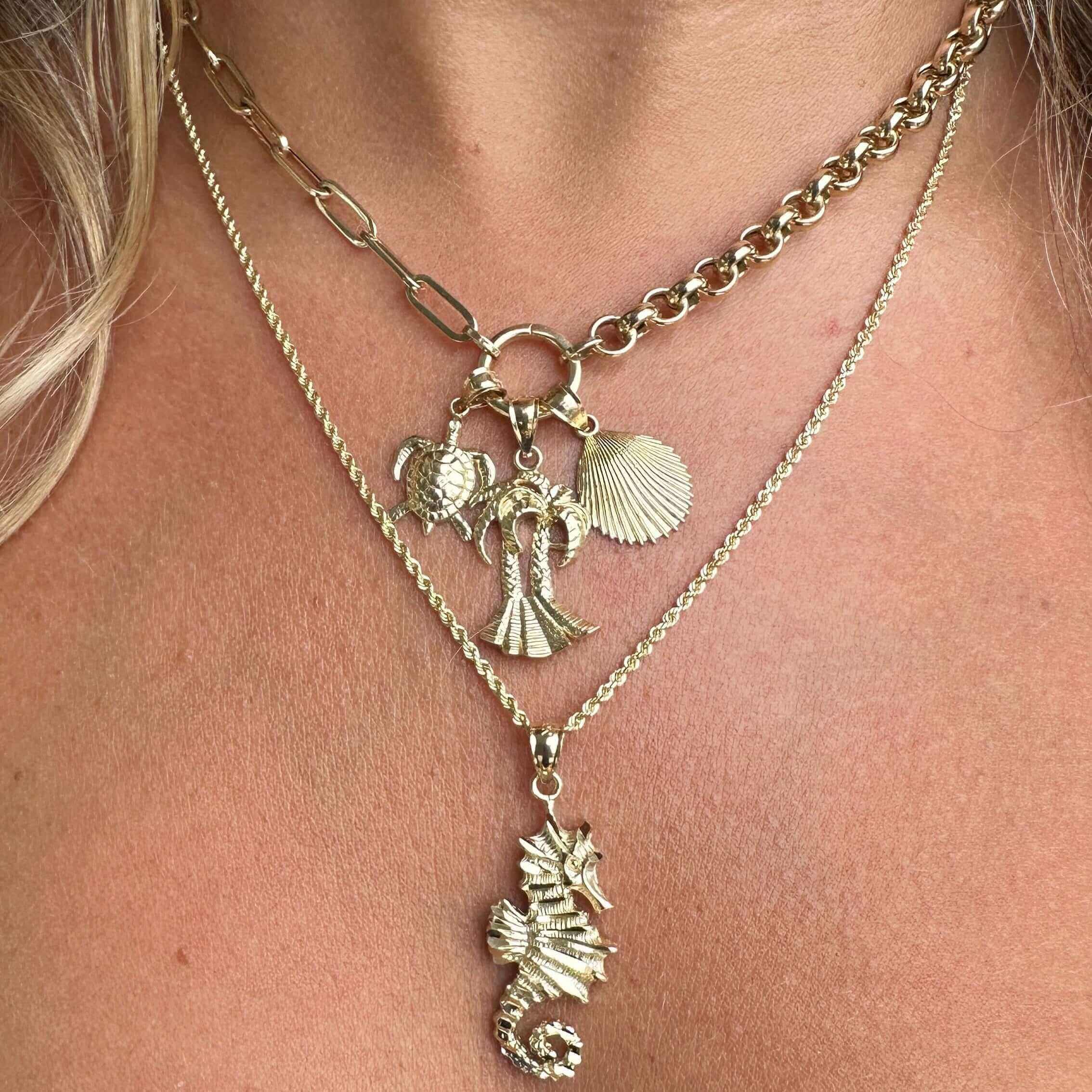 Woman wearing layered gold necklaces featuring sea life charms from our jewelry collection.
