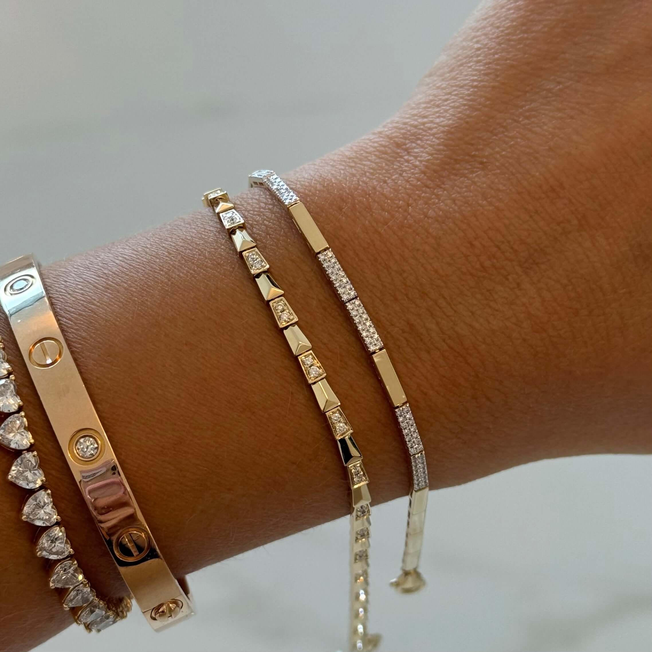 14K Gold Micro Pave Diamond Bars Pattern Bracelet worn alongside other elegant bracelets on a wrist.