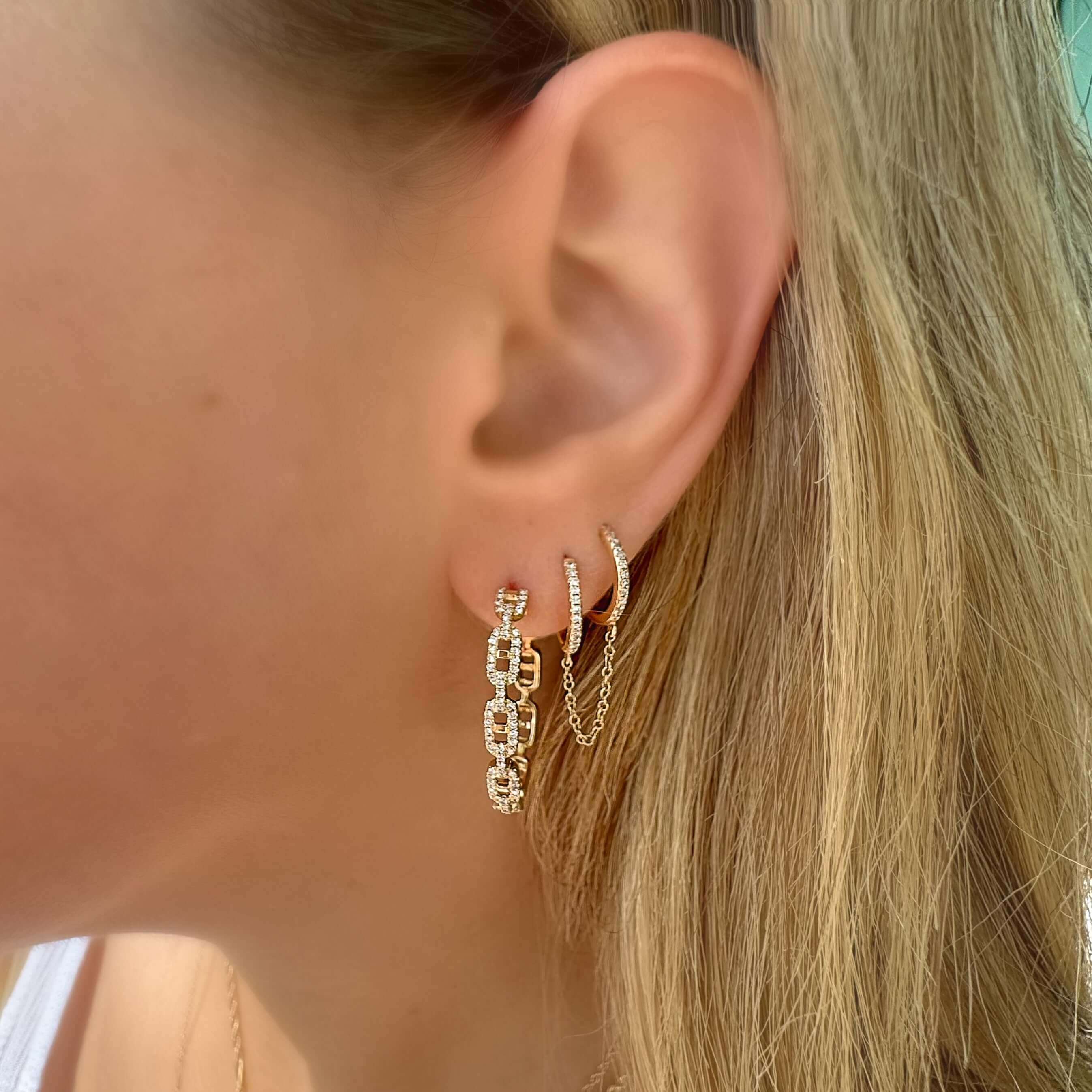 Woman wearing layered gold chain earrings with intricate design from our jewelry collection