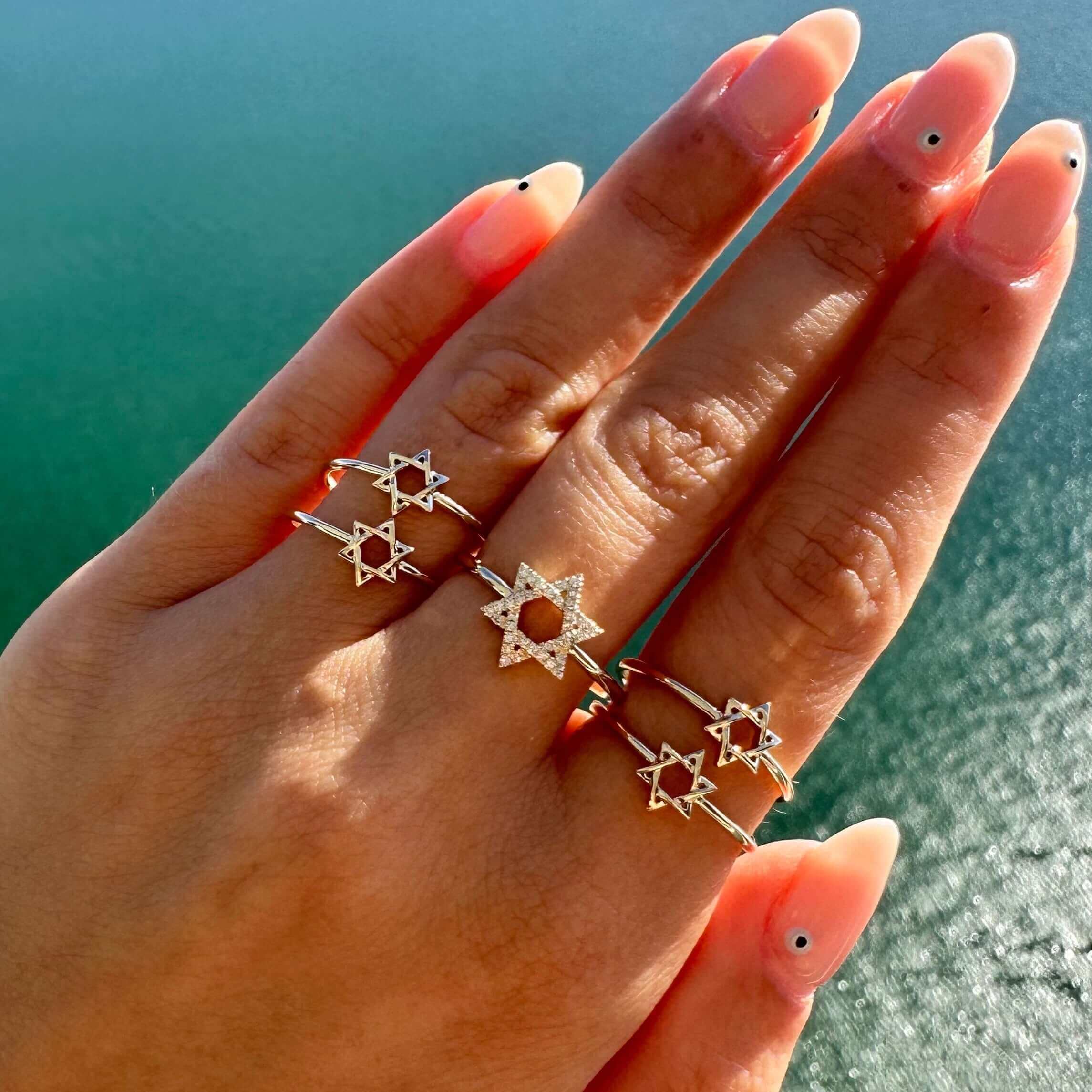 Silver star rings on hand by the ocean, luxury jewelry from our collection