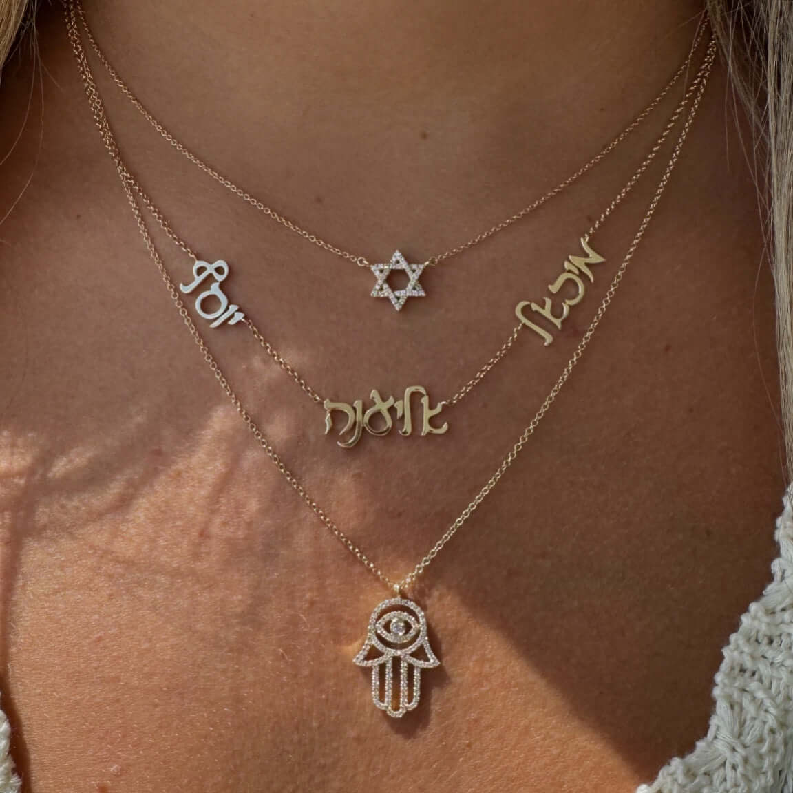 Layered gold necklaces featuring hamsa, evil eye, and star designs, symbolizing protection and spirituality.