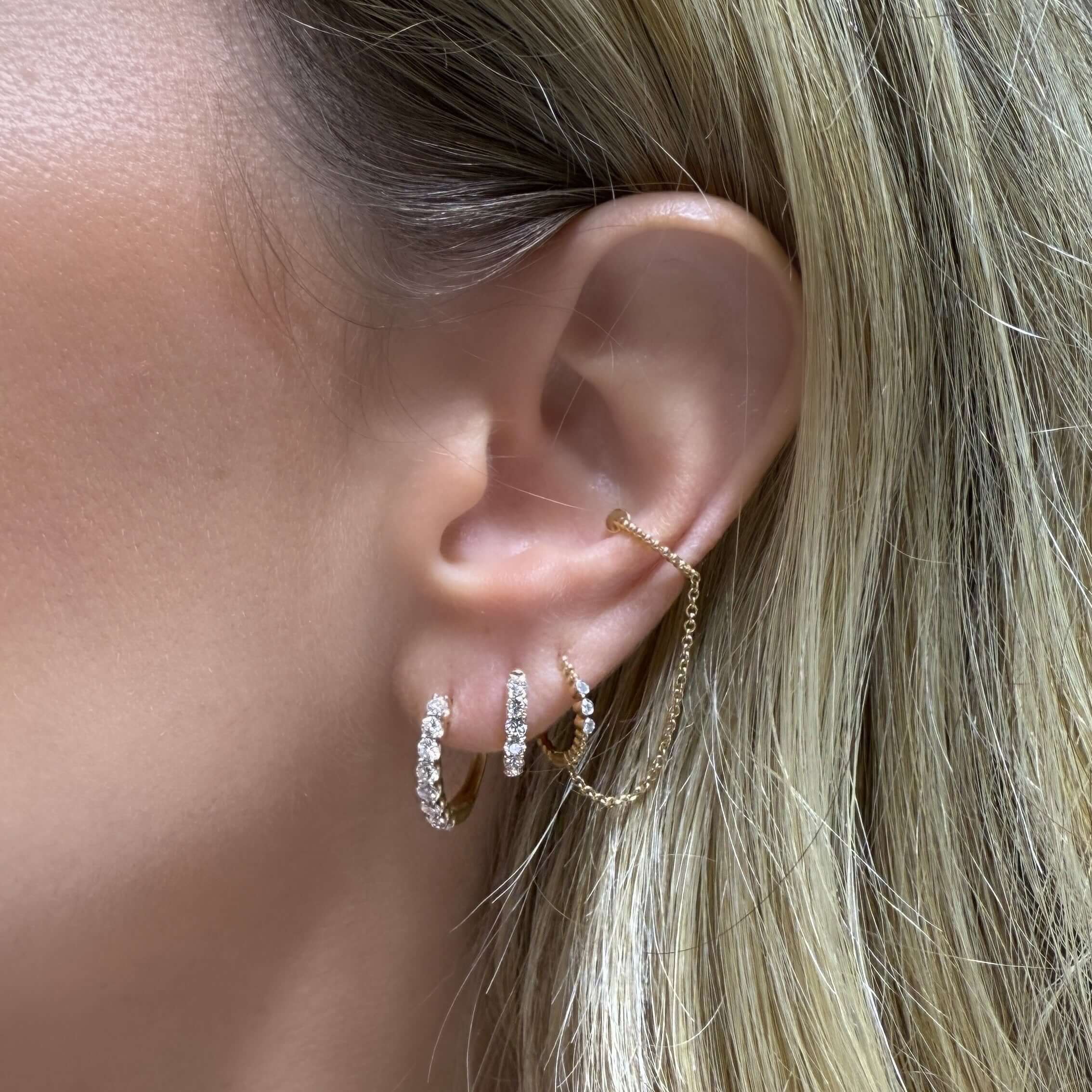 14K Gold Classic Pave Diamond Huggies worn on a model's ear showcasing elegant diamond detailing.