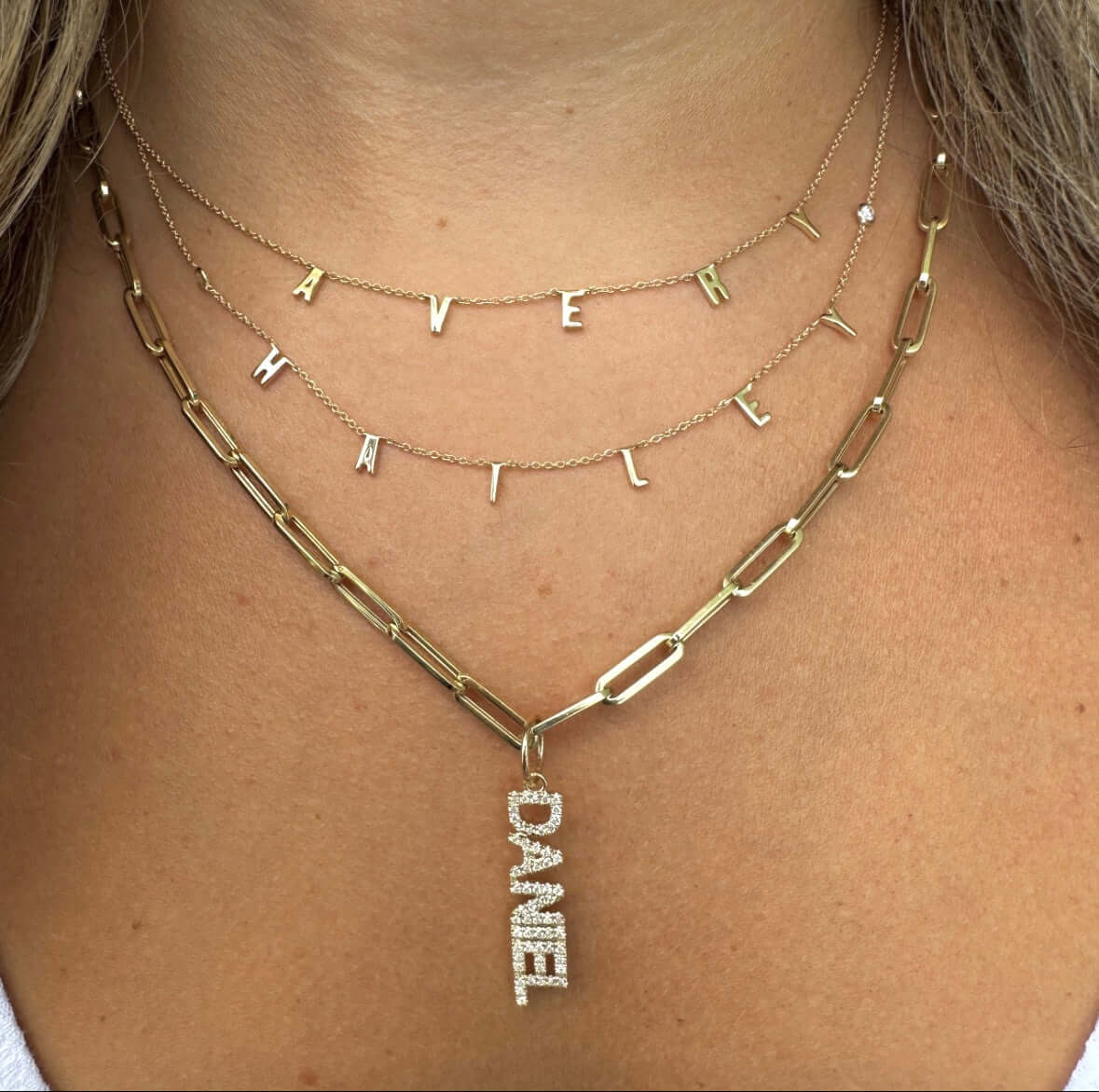 Close-up of gold layered name necklaces featuring the names Avery, Hailey, and Daniel, showcasing our personalized jewelry collection.