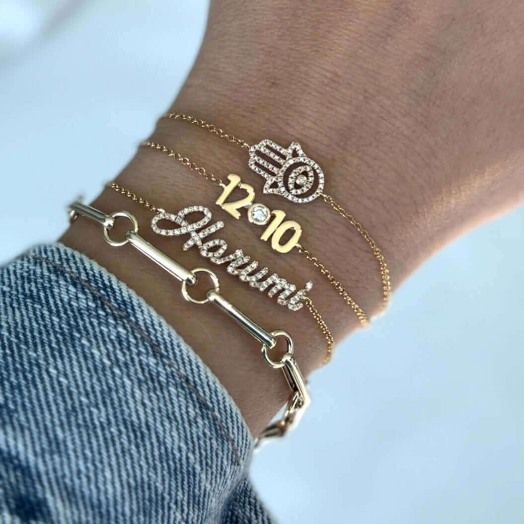 14K gold personalized script nameplate diamond bracelet showcased on wrist, featuring elegant design and sparkling details.