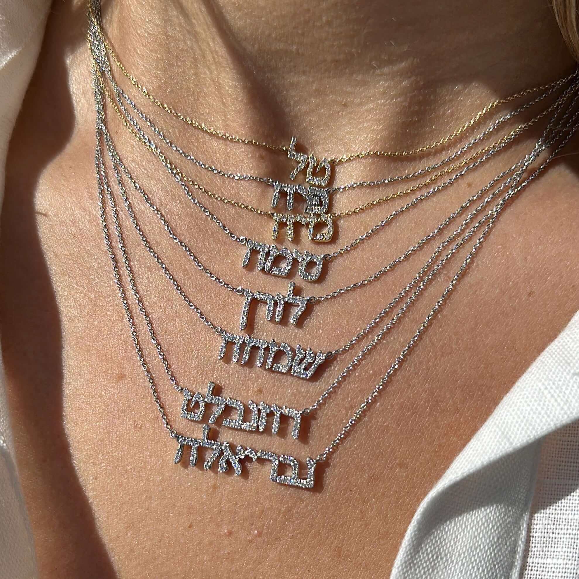 Personalized Hebrew Diamond Nameplate Necklace displayed with multiple nameplates in different fonts and styles by Izakov Fine Jewelry.