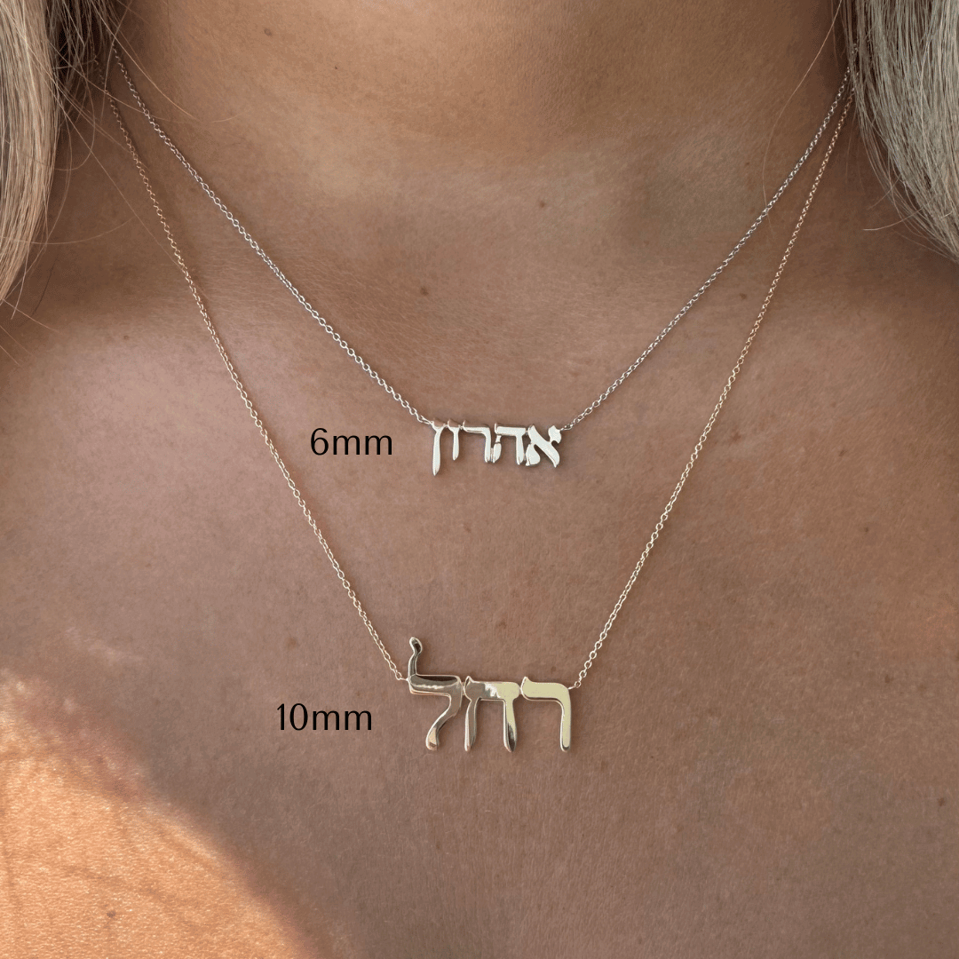 Woman wearing two delicate Hebrew name necklaces in gold from our jewelry brand, featuring 6mm and 10mm pendant sizes.