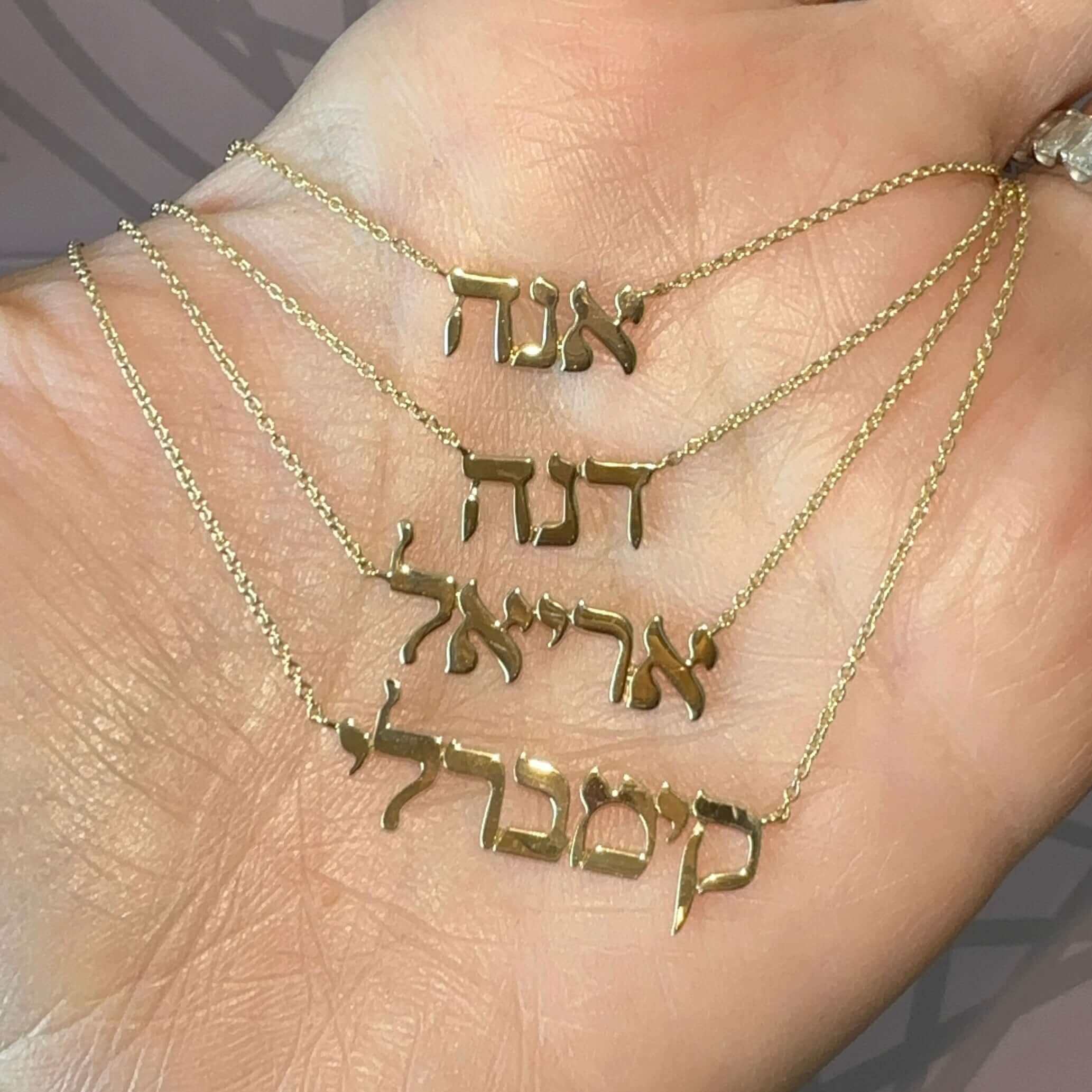Personalized Hebrew Nameplate Gold Necklace displayed on a hand showcasing unique Hebrew names in 14K gold.