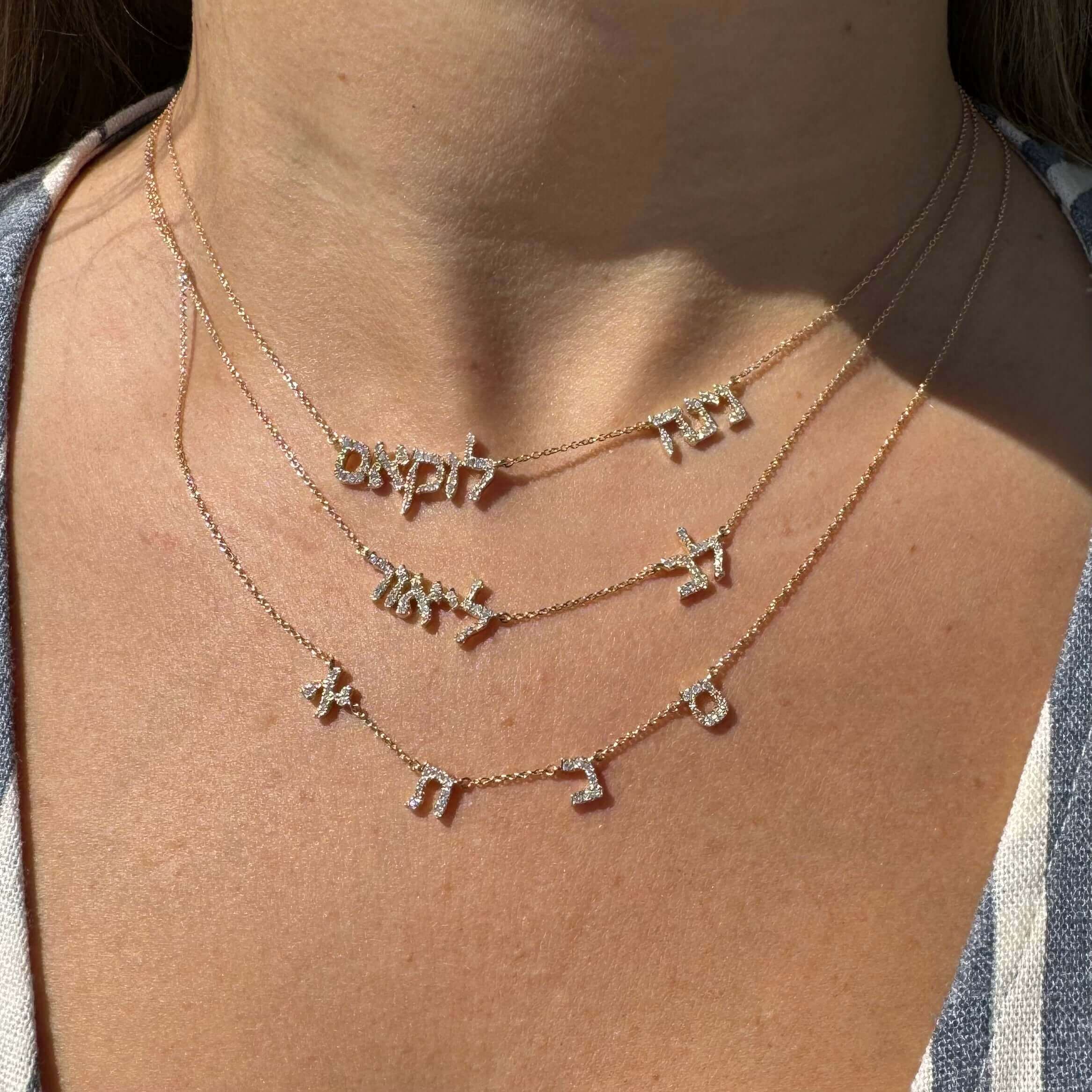 Layered gold necklaces with Hebrew letters showcased on a model's neck, highlighting elegant jewelry from our brand.