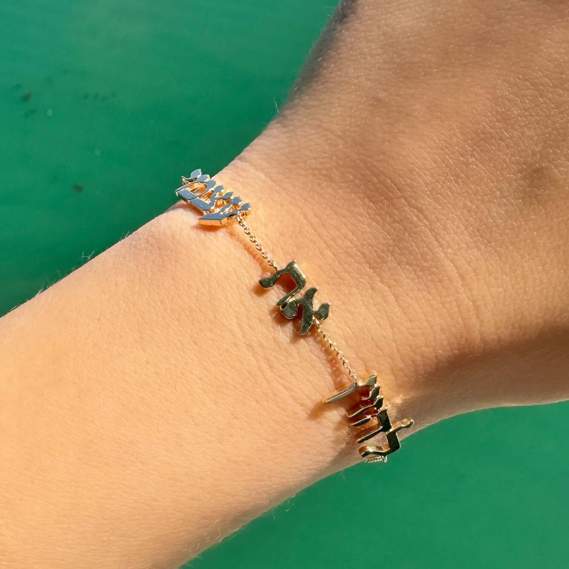 Gold bracelet with unique name design displayed on wrist from jewelry collection