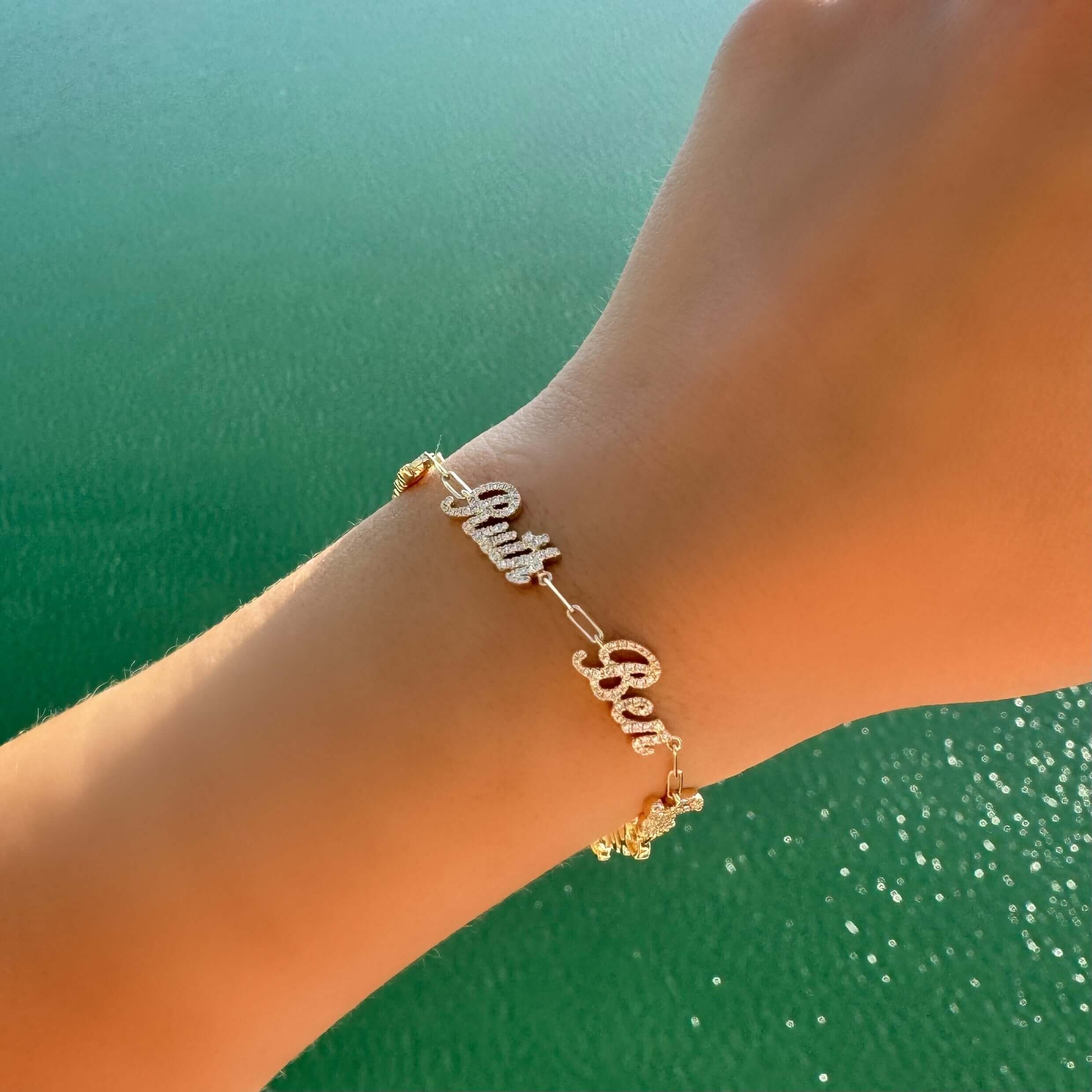 Gold personalized "Bubba" bracelet with sparkling detail on wrist by the sea